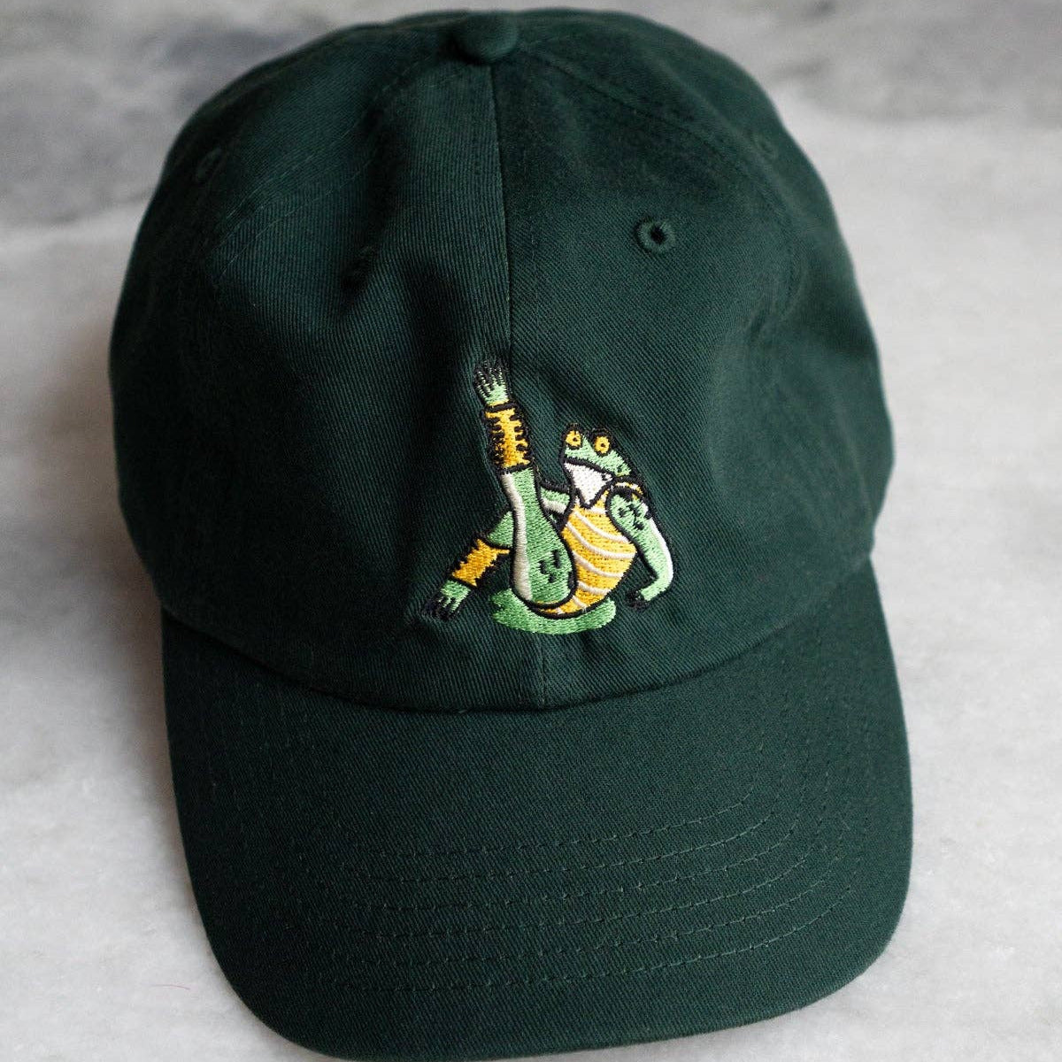 Green cap with a embroidered design on a gray surface