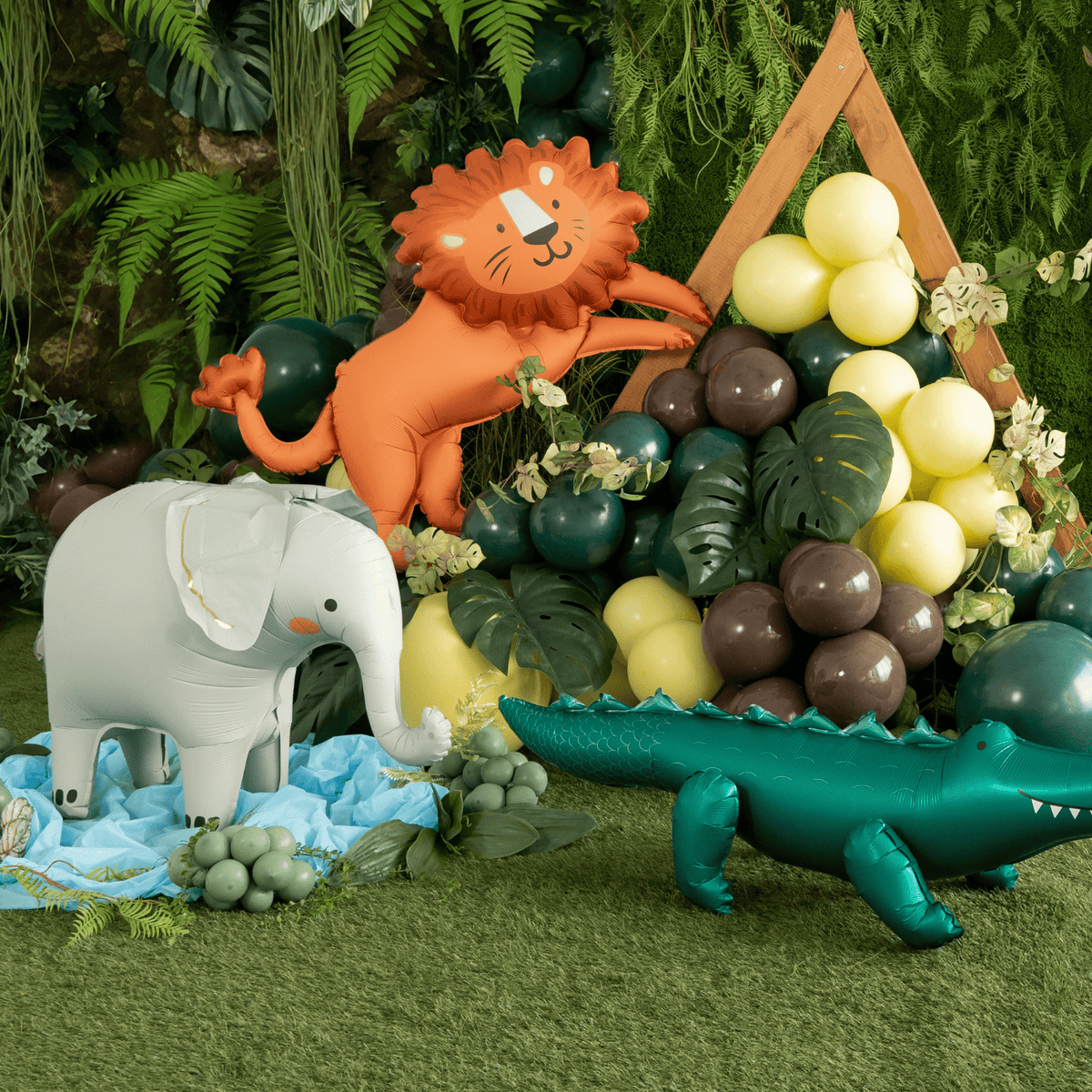 Toy lion, elephant, and crocodile with balloons in a jungle setting