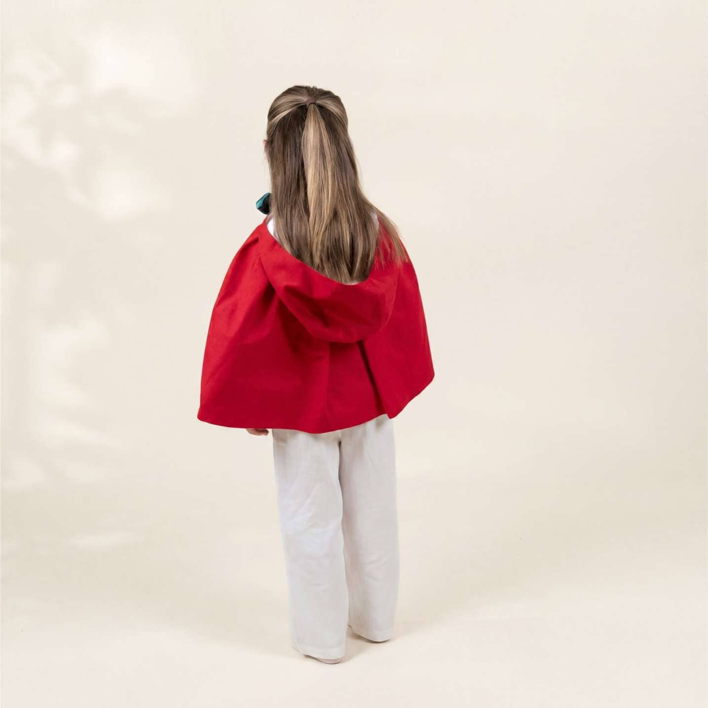 Person wearing a red cape on a plain background