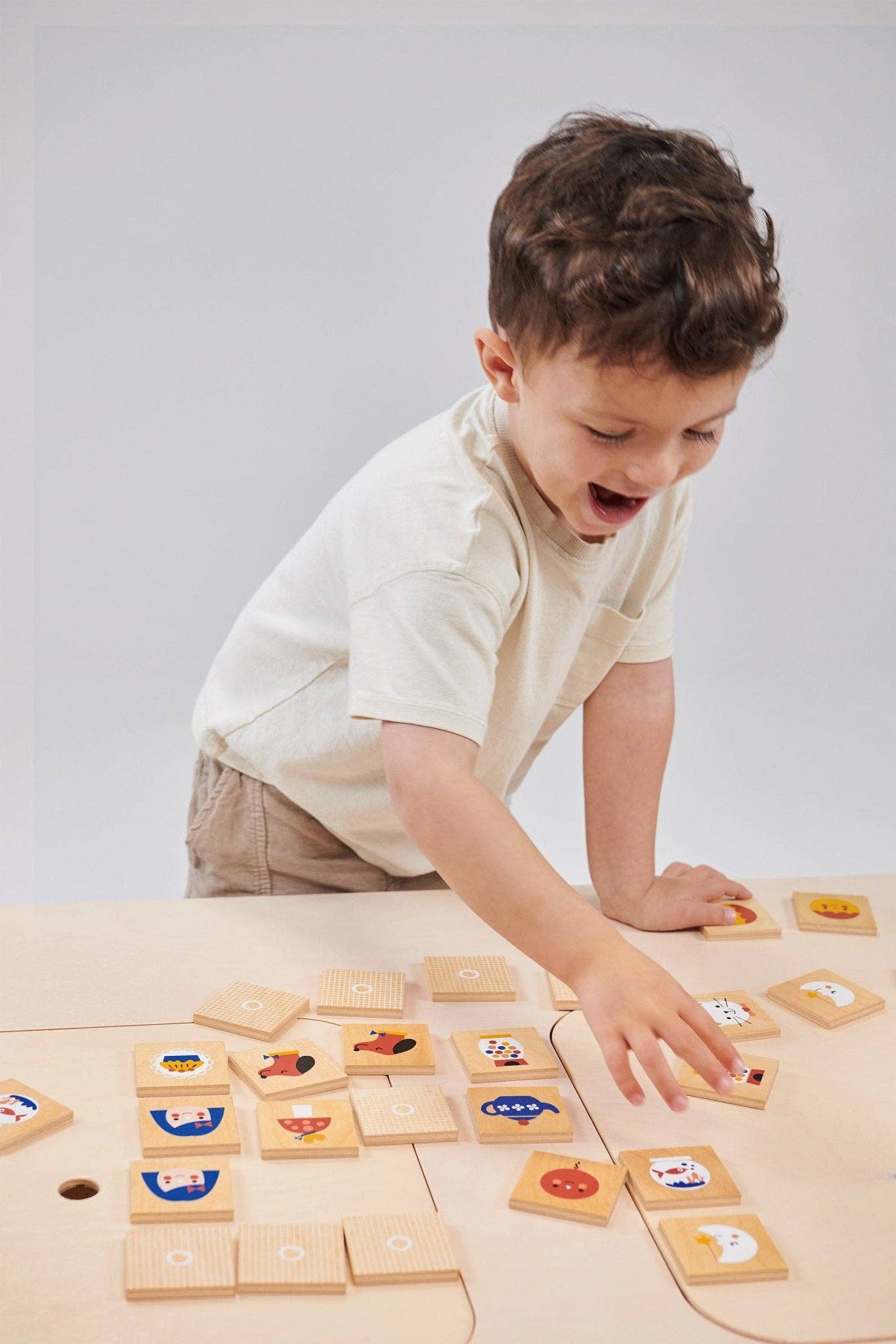Child playing with wooden educational blocks on a light surface