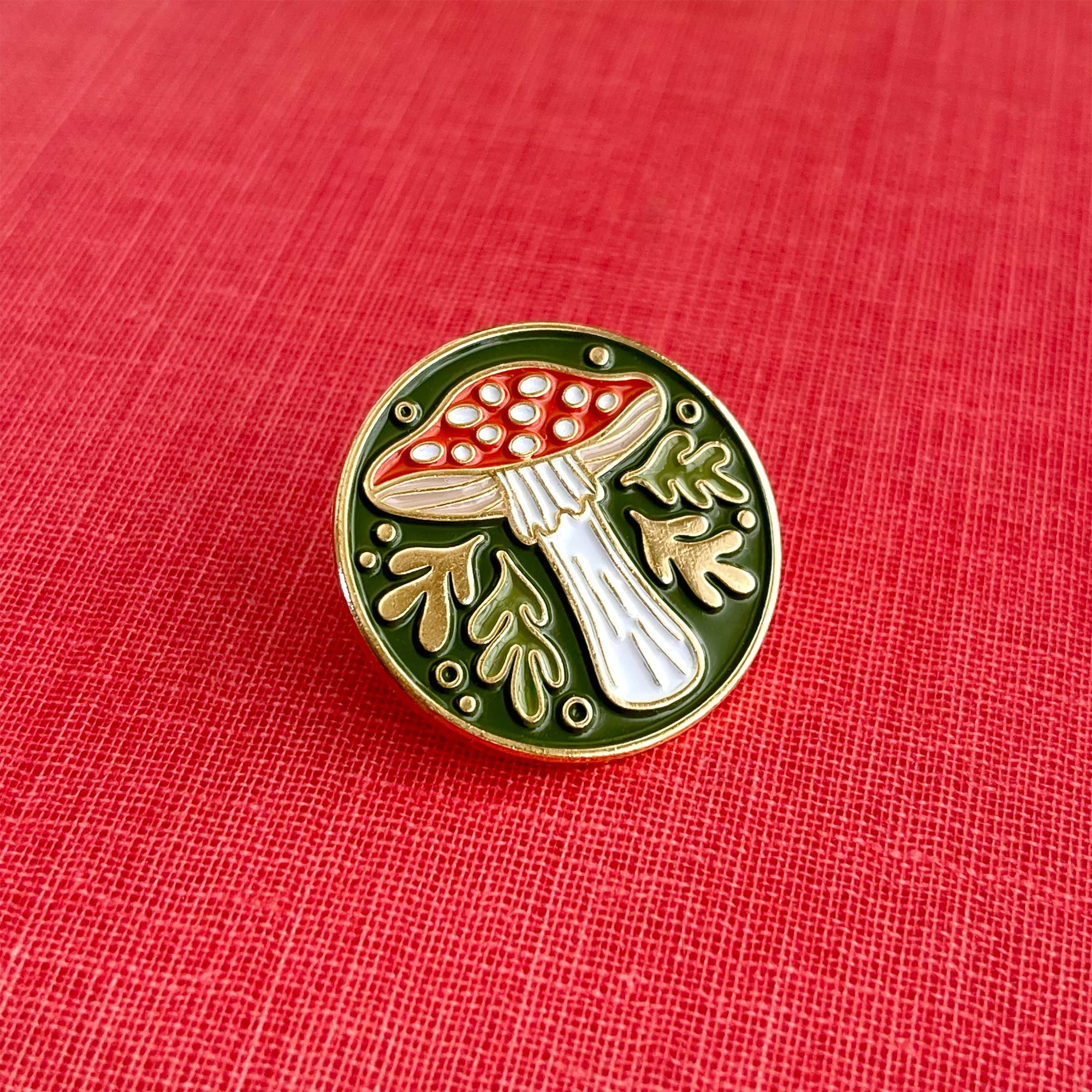 Mushroom-shaped pin on a red fabric background