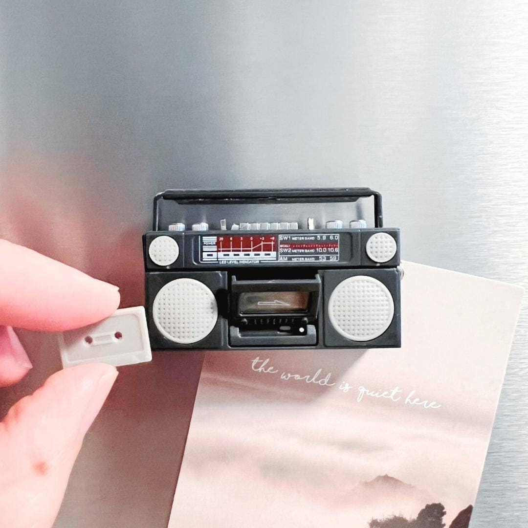 Small black and white radio with cassette player held over a scenic photo