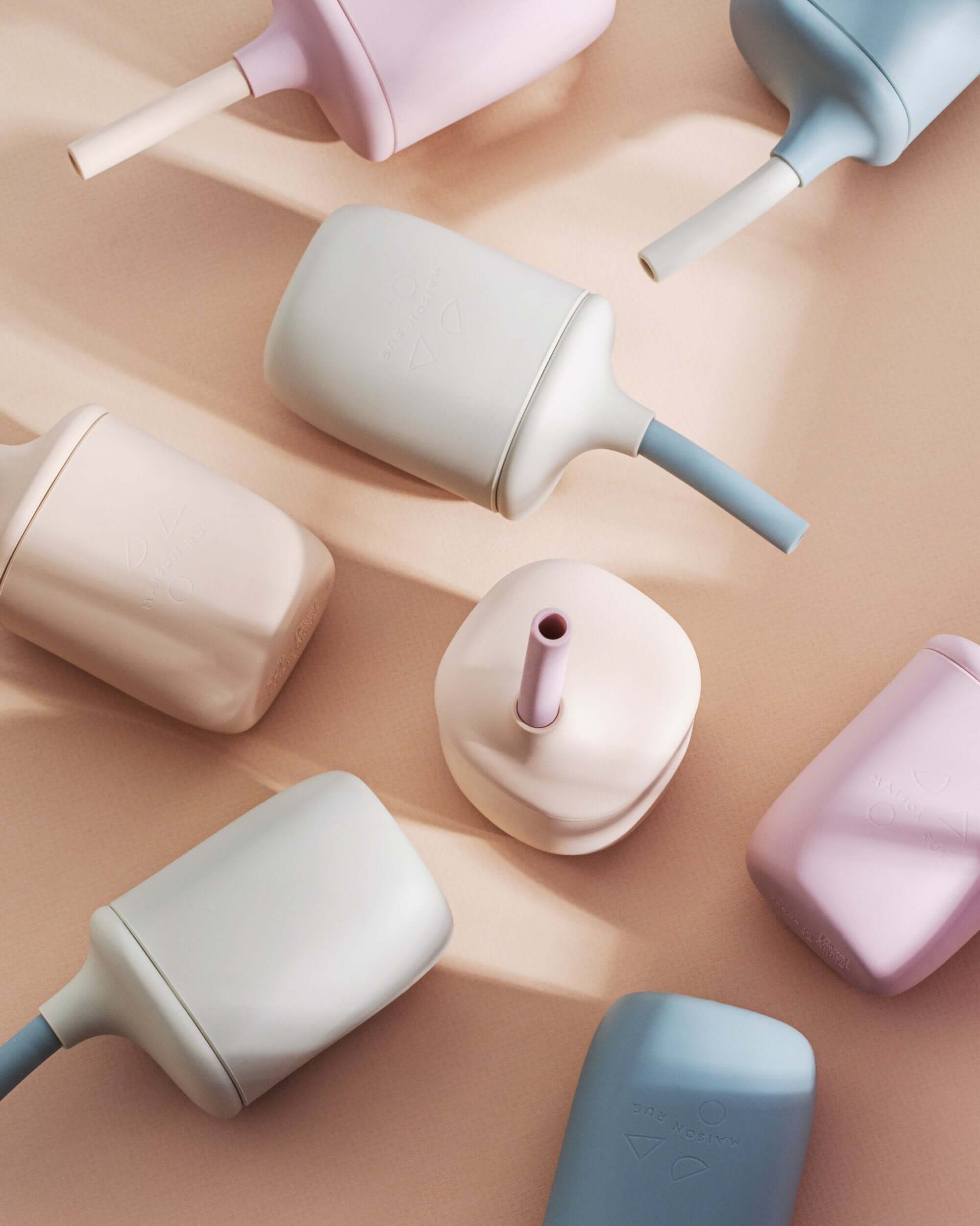 Colorful silicone cups with handles and straws on a beige background