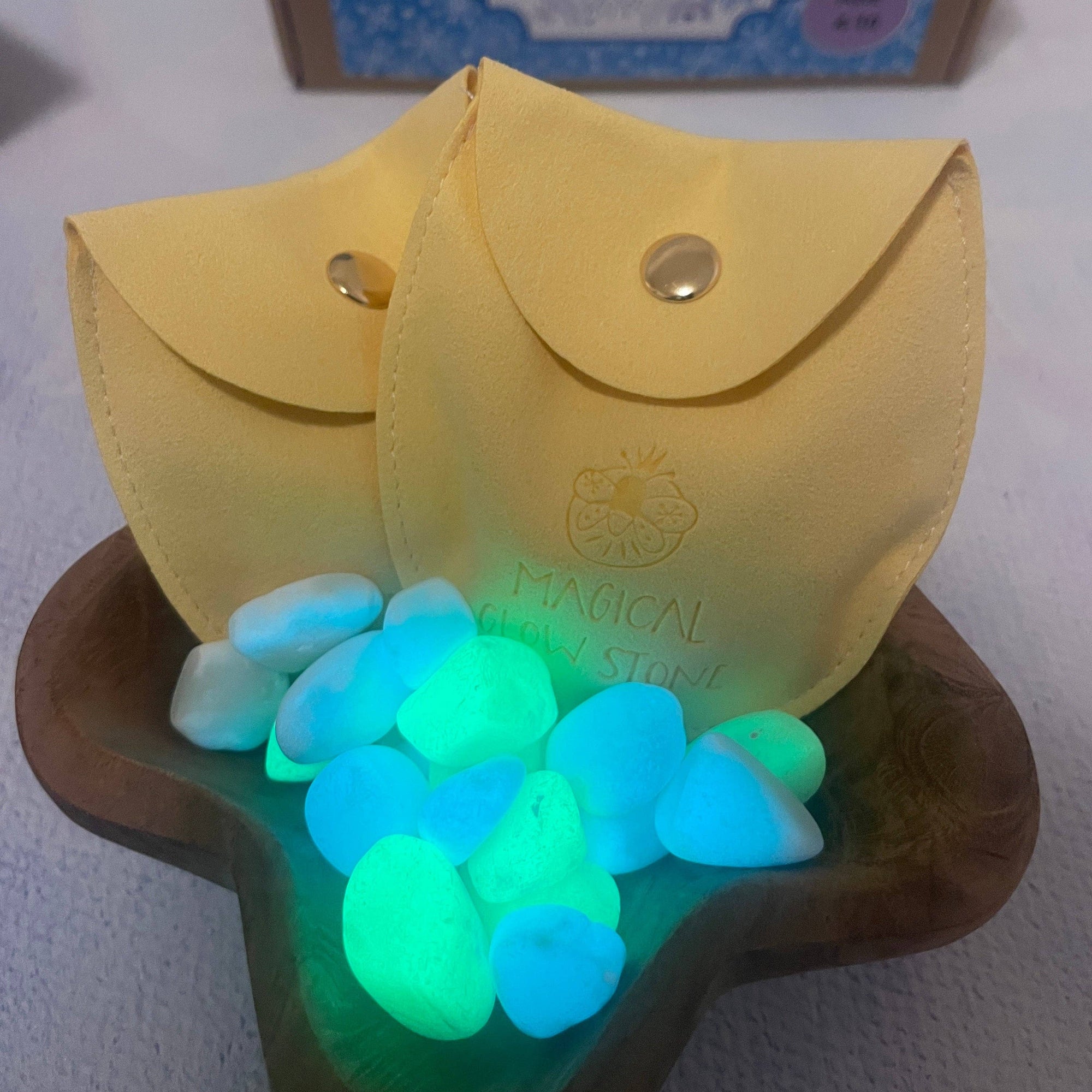 Glowing stones in a wooden bowl with a yellow pouch and 'Ice Wonder' packaging in the background.