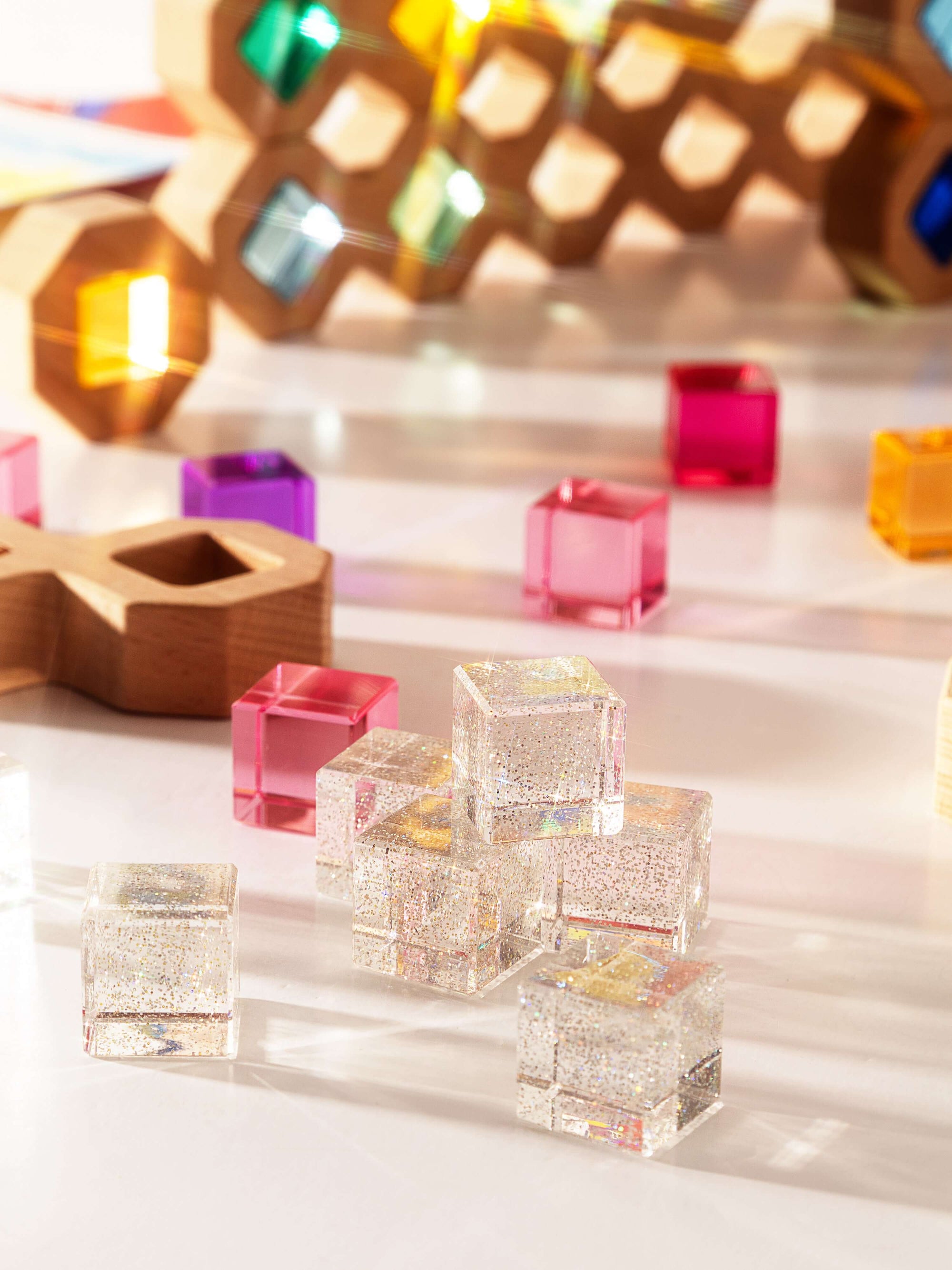 Colorful transparent cube-shaped objects on a reflective surface with a blurred geometric background.