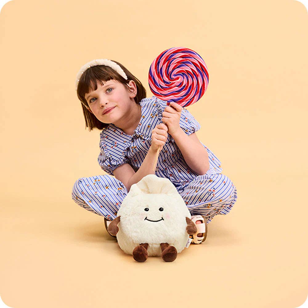 Child holding a plush toy and a large lollipop against a beige background