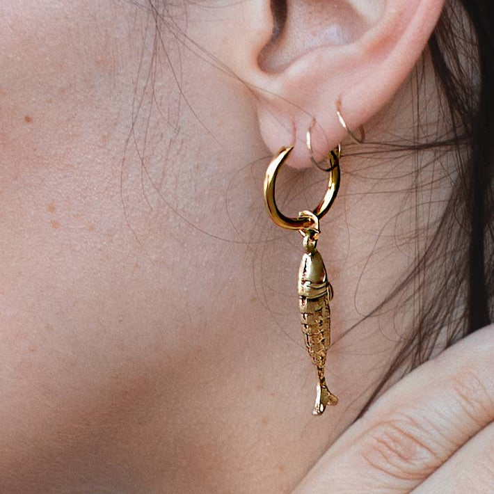 Gold fish-shaped earring worn by a person