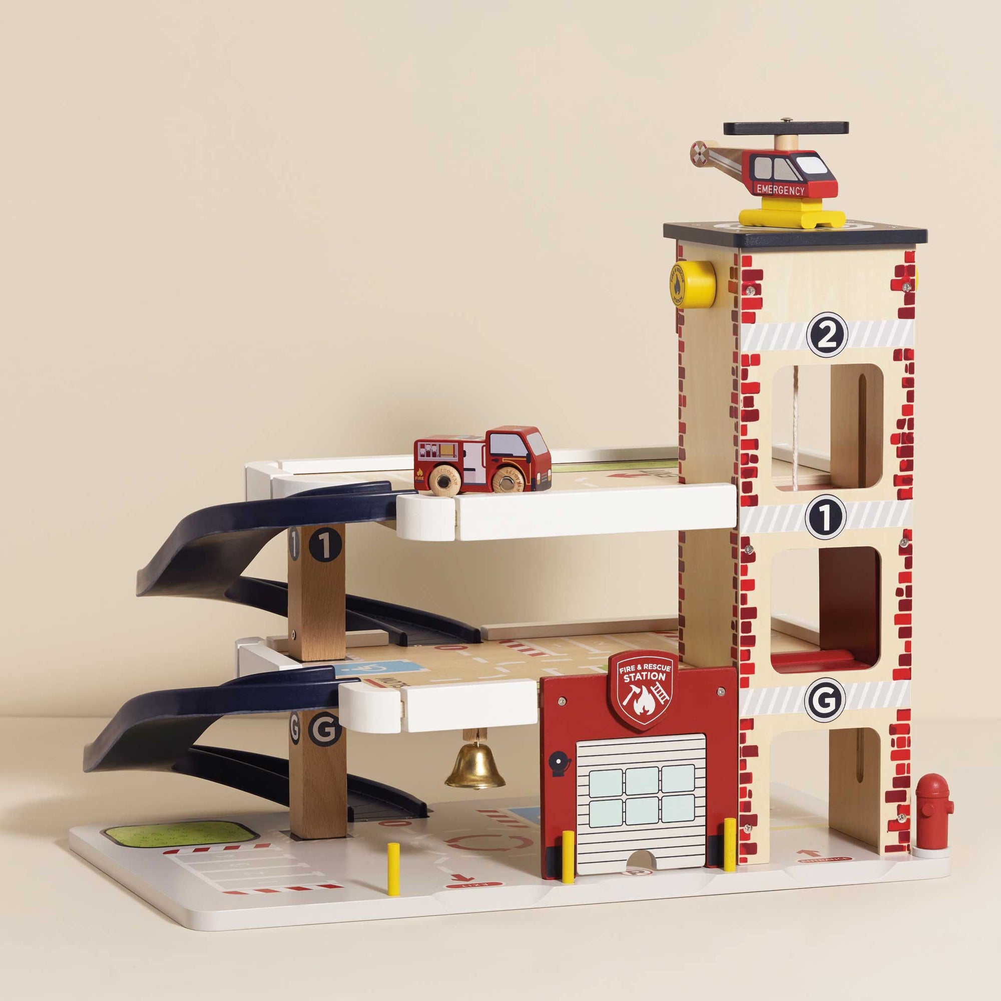 Toy fire station with cars and helicopter on a beige background