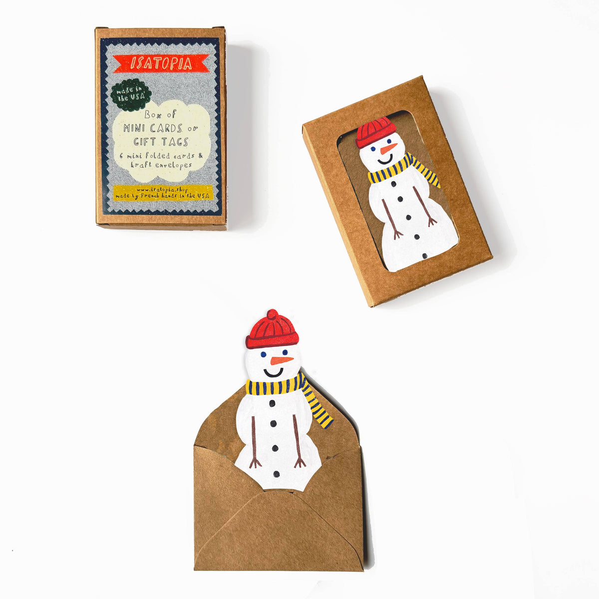 A set of holiday greeting cards and envelopes from the brand HAYOTIA, featuring a cute snowman character wearing a red hat and yellow striped scarf. The set includes a small retail box, a windowed kraft envelope, and a flat envelope with a printed snowman card.