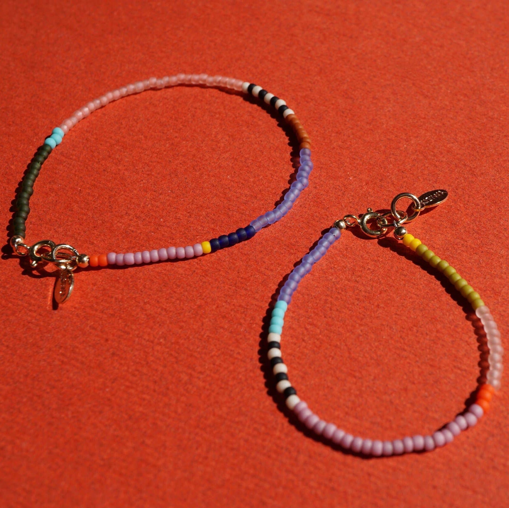 Two beaded bracelets on a red background