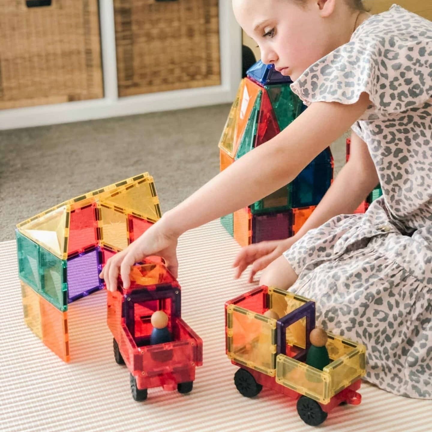 Child playing with colorful magnetic building blocks on a light surface.