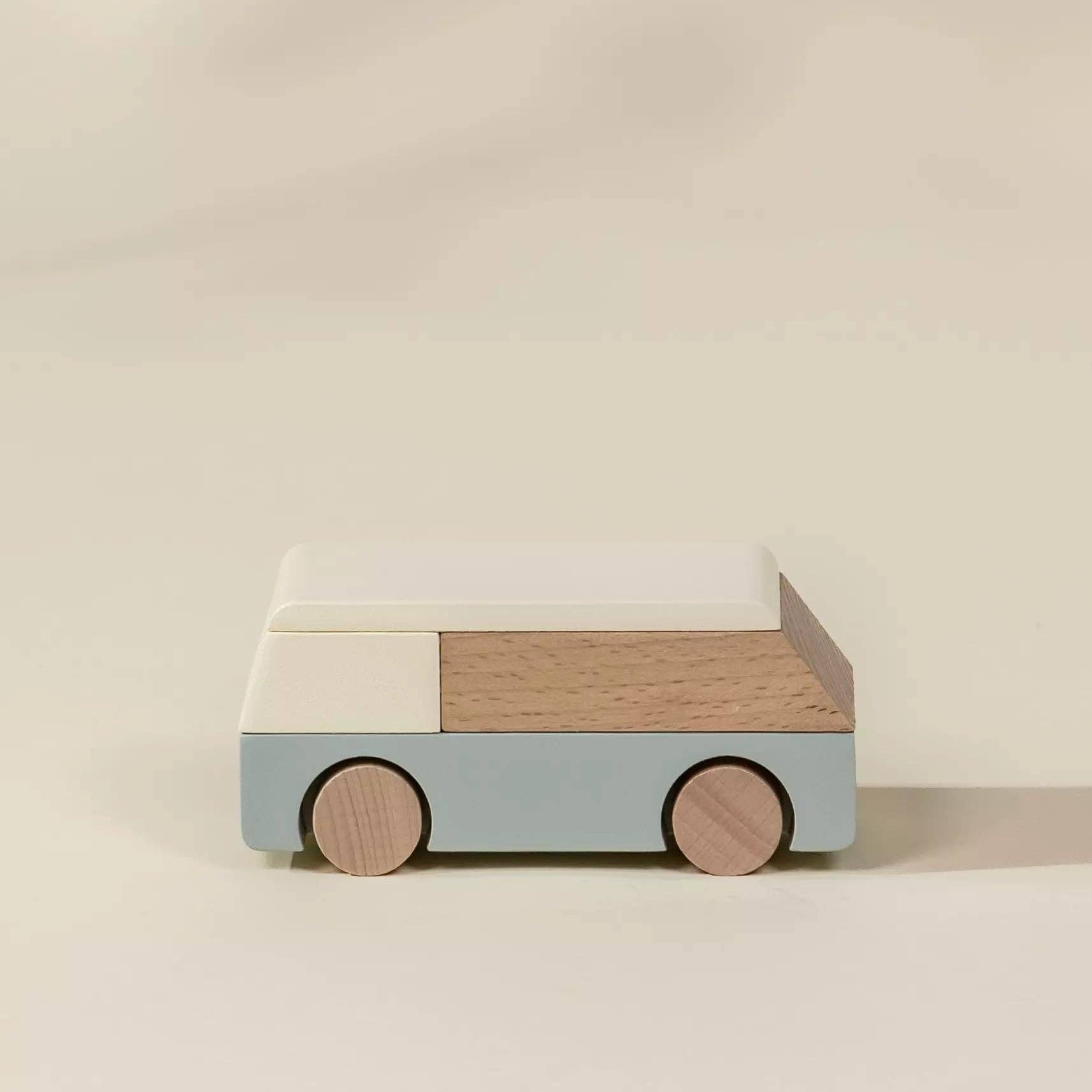 Wooden toy car with a light blue body and brown wheels on a beige background