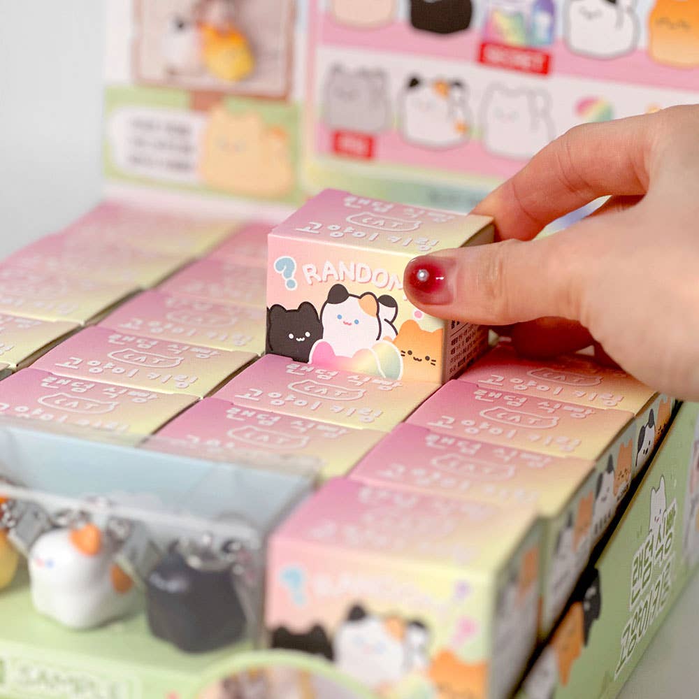 Hand reaching for a small box among a collection of colorful boxes with cartoon designs.