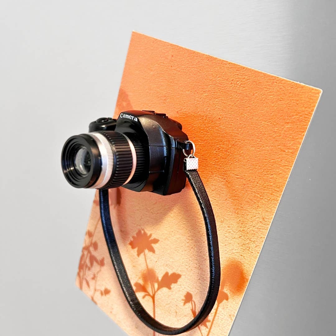 Camera with a strap on an orange surface with floral patterns