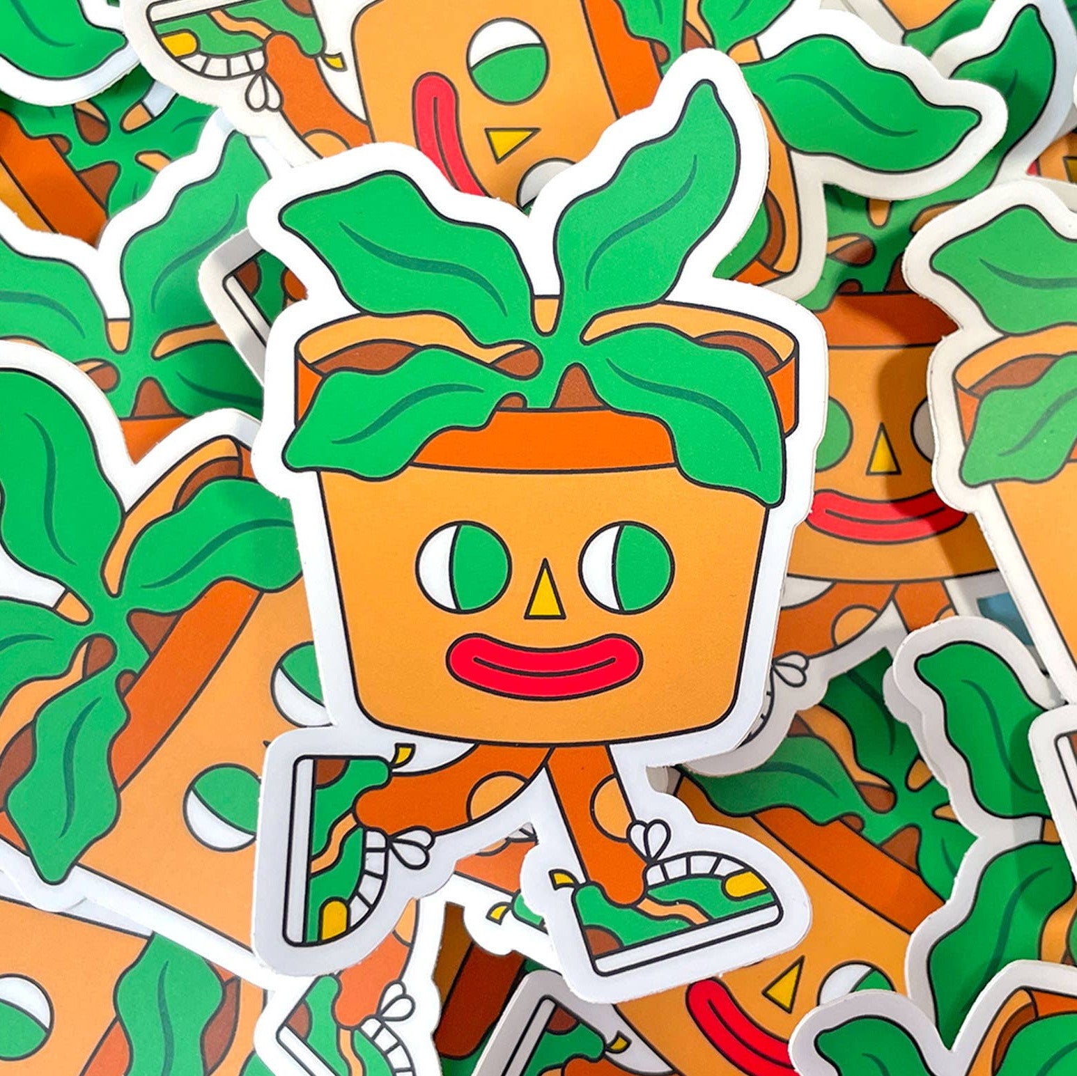 Sticker design of a smiling potted plant with a face on an orange background.