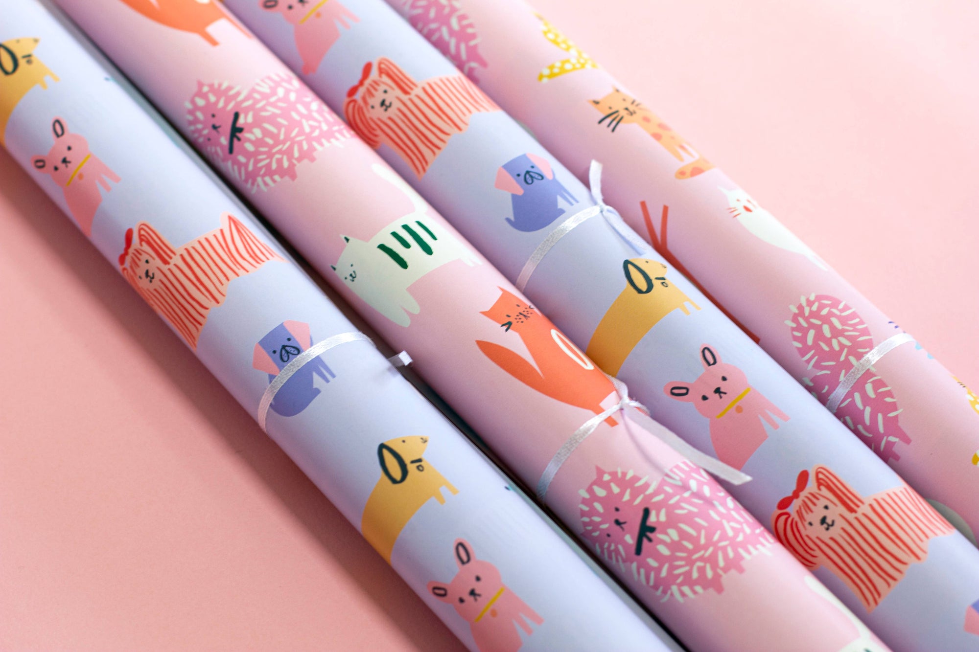 Three rolls of colorful paper with animal illustrations on a pink background