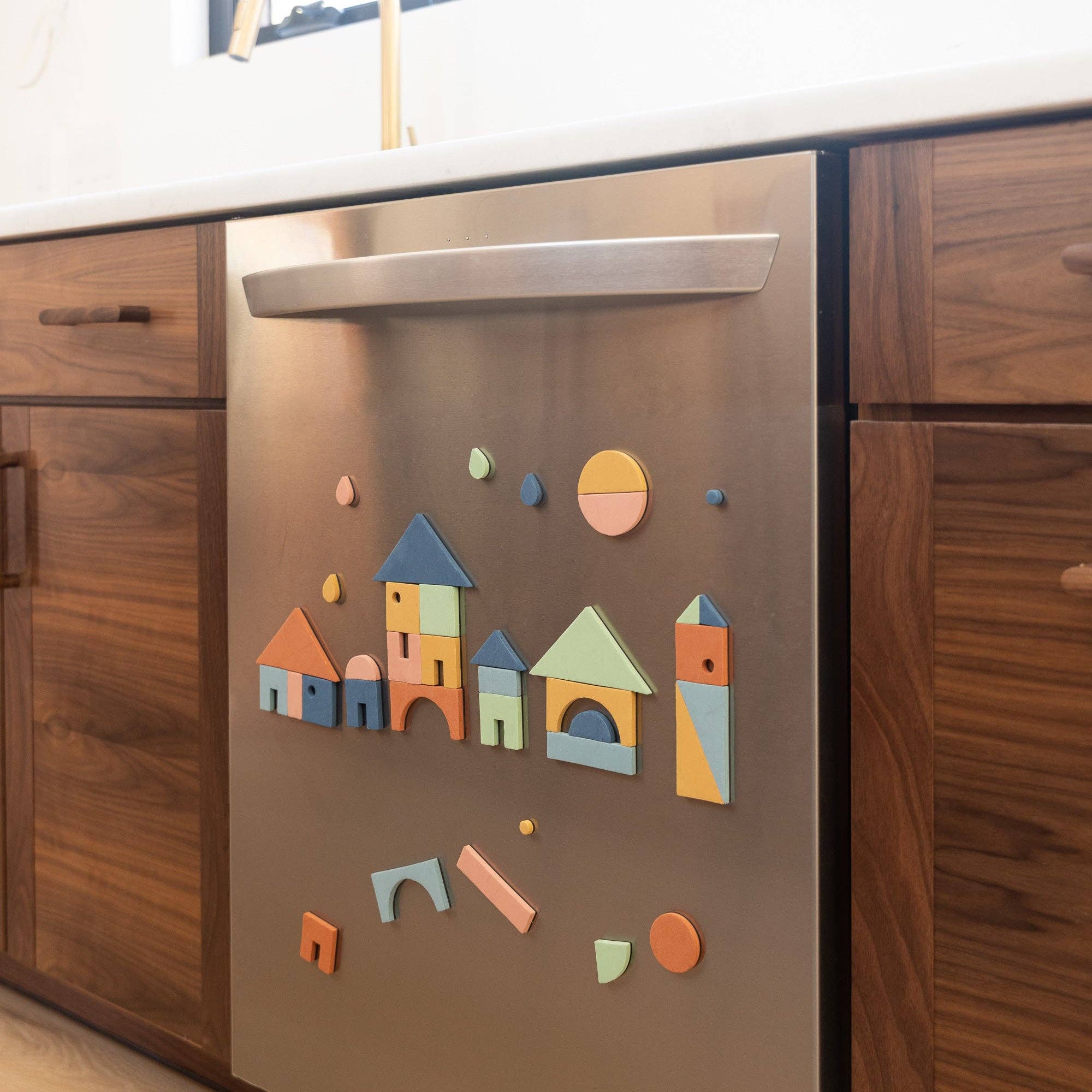 Stainless steel appliance with colorful magnetic shapes on a wooden cabinet background