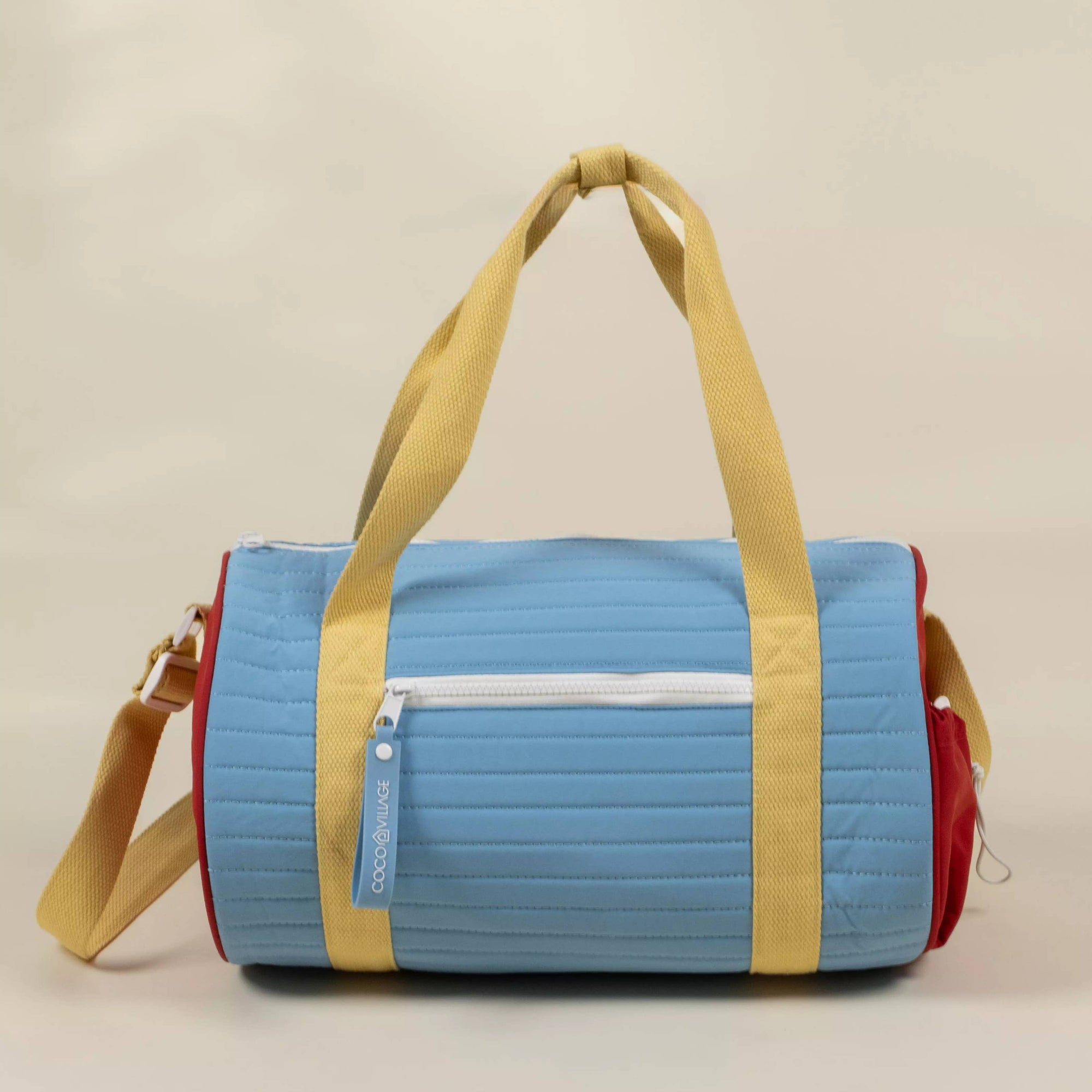 Multicolored duffel bag with blue, yellow, and red sections on a beige background