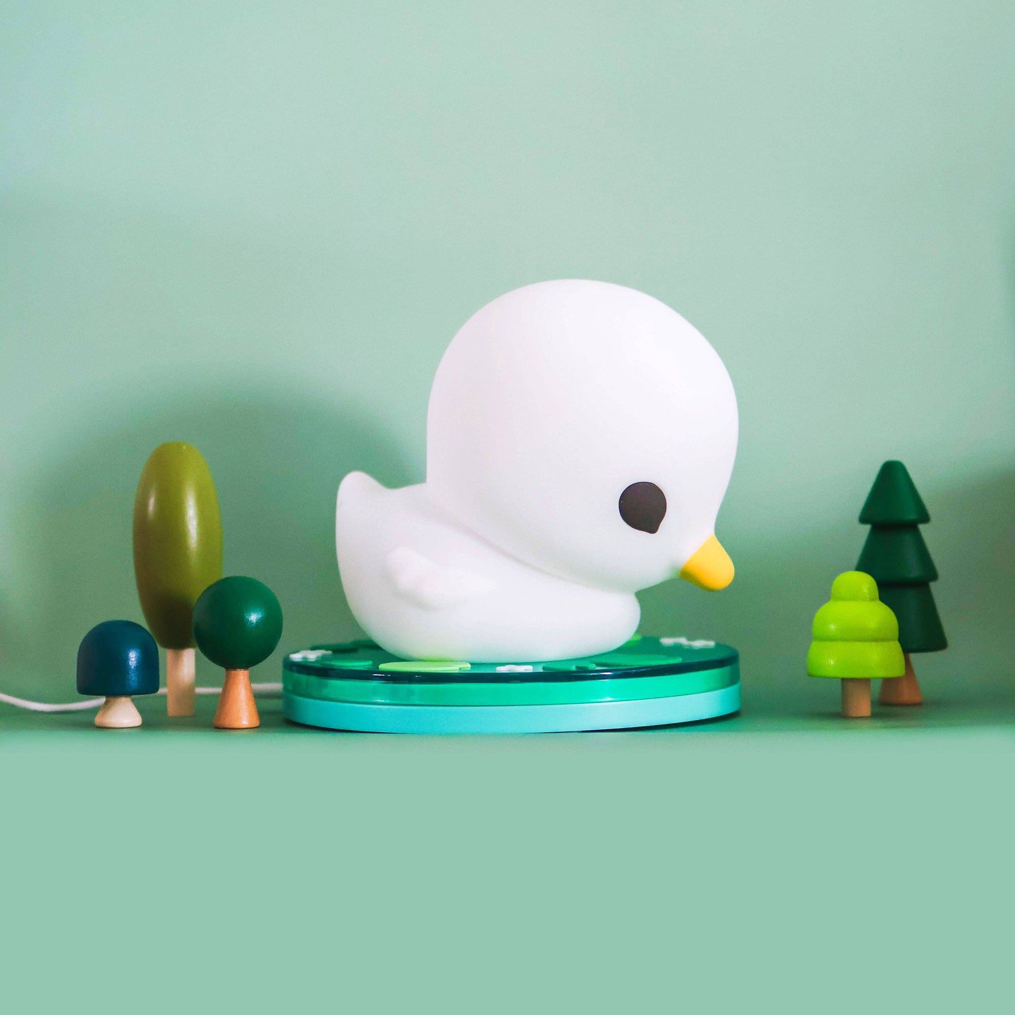 White duck-shaped lamp with green base on a light green background