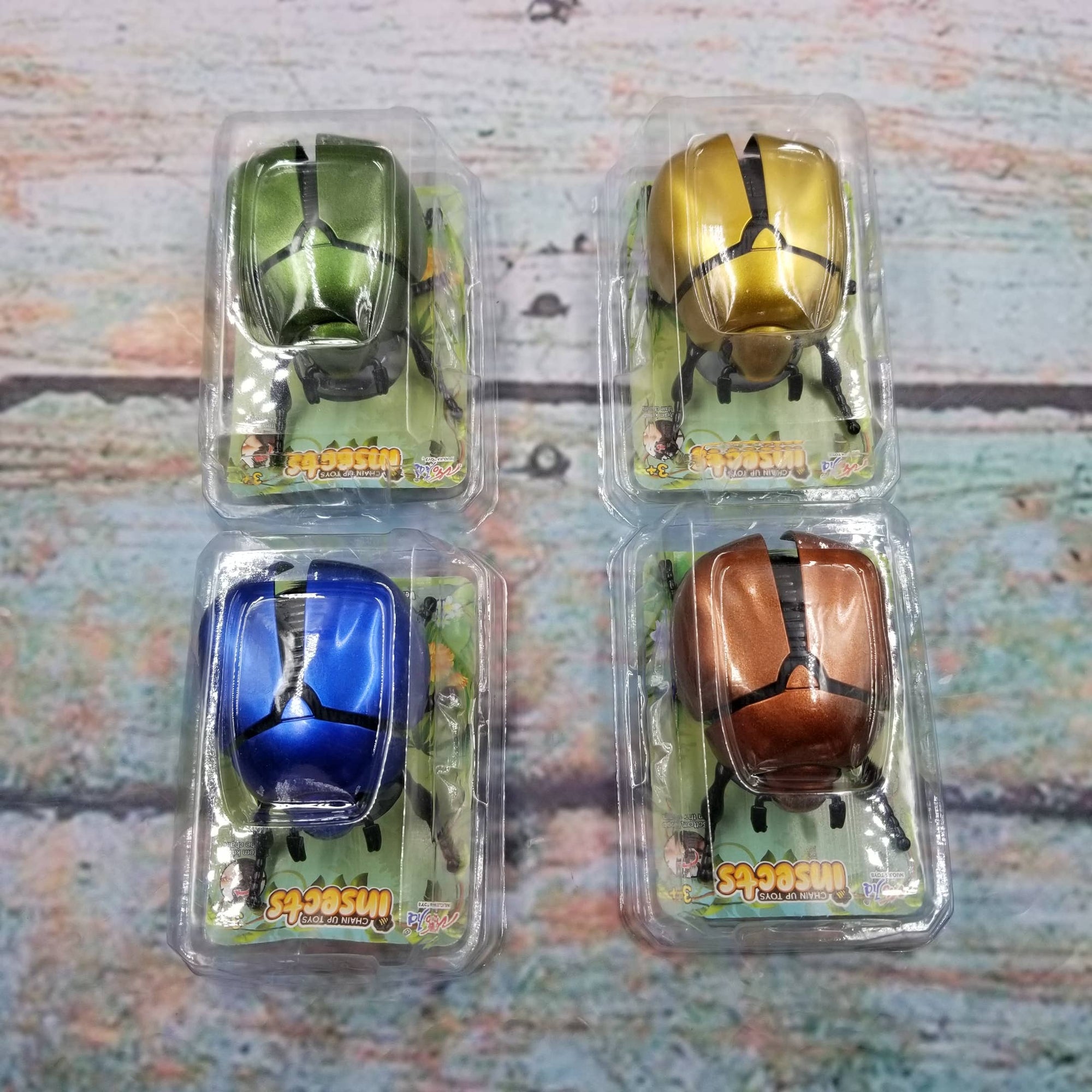Four packaged toy beetles on a textured surface
