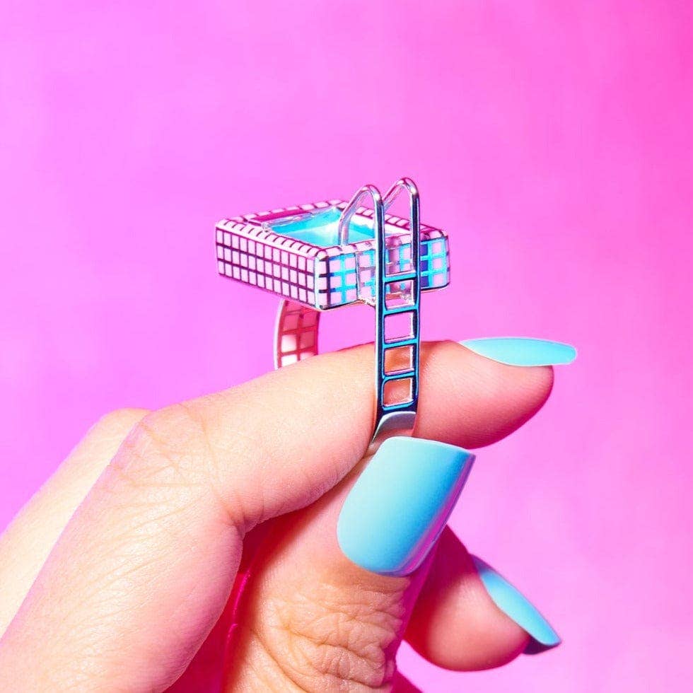 Hand holding a small, decorative ladder against a pink background