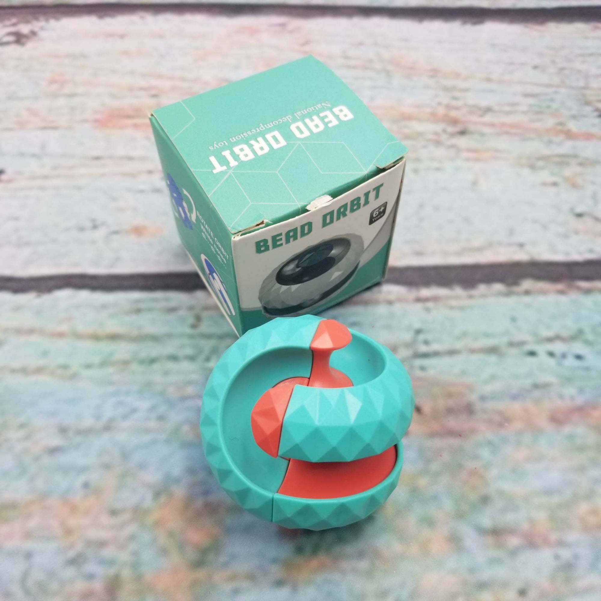 Turquoise and red puzzle toy with packaging on a textured surface