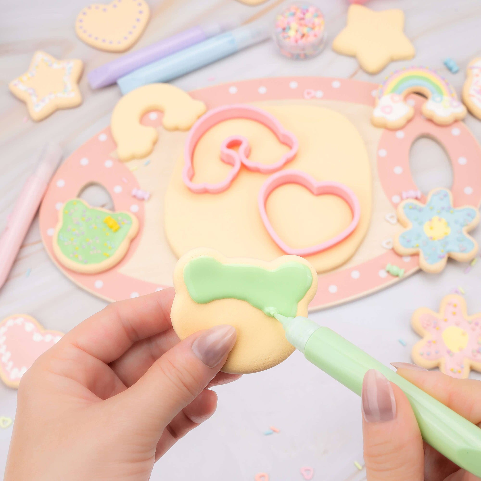 Decorative cookie with pastel colors and a hand holding a green tool on a colorful background.