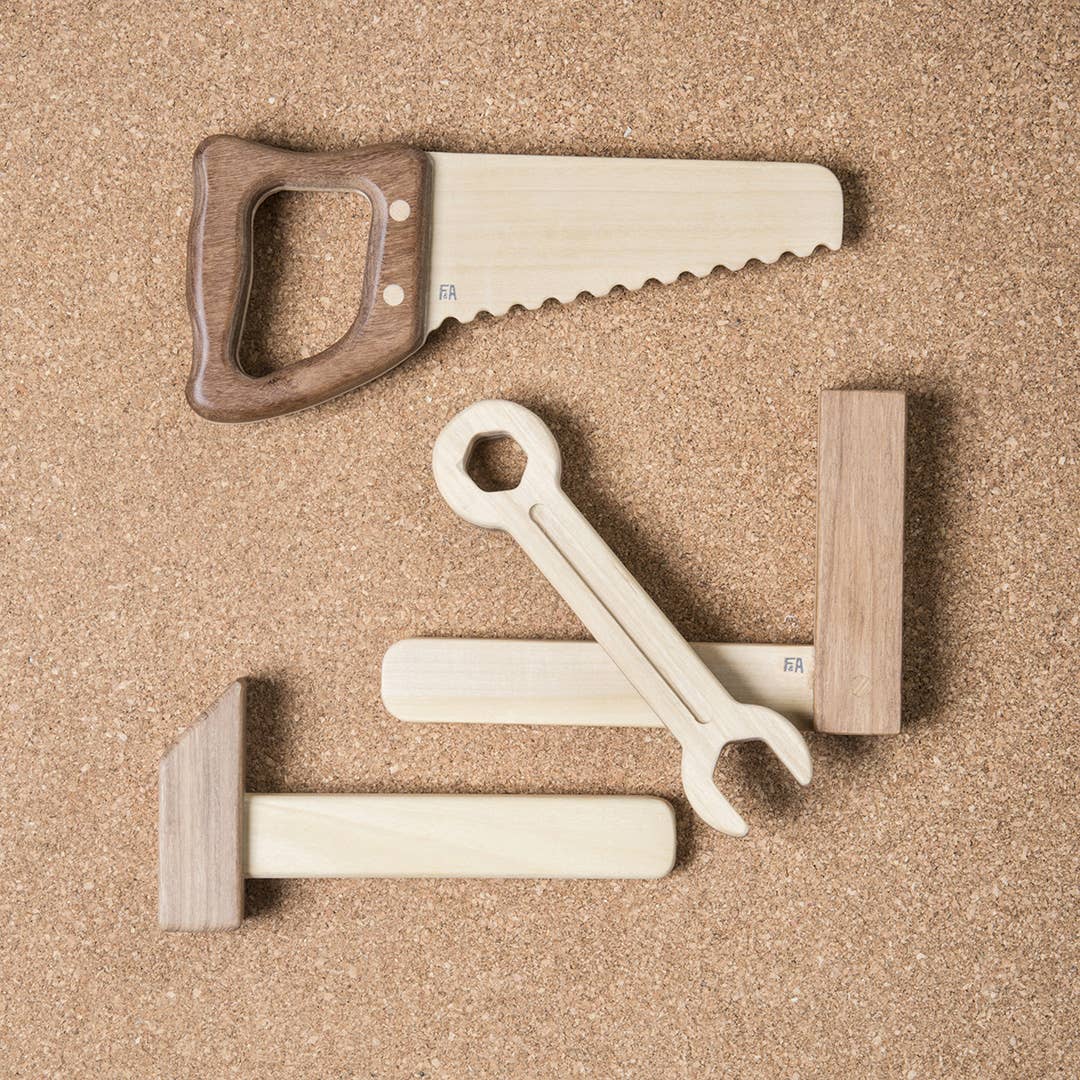 Wooden tools including a saw, hammer, and wrench on a brown surface