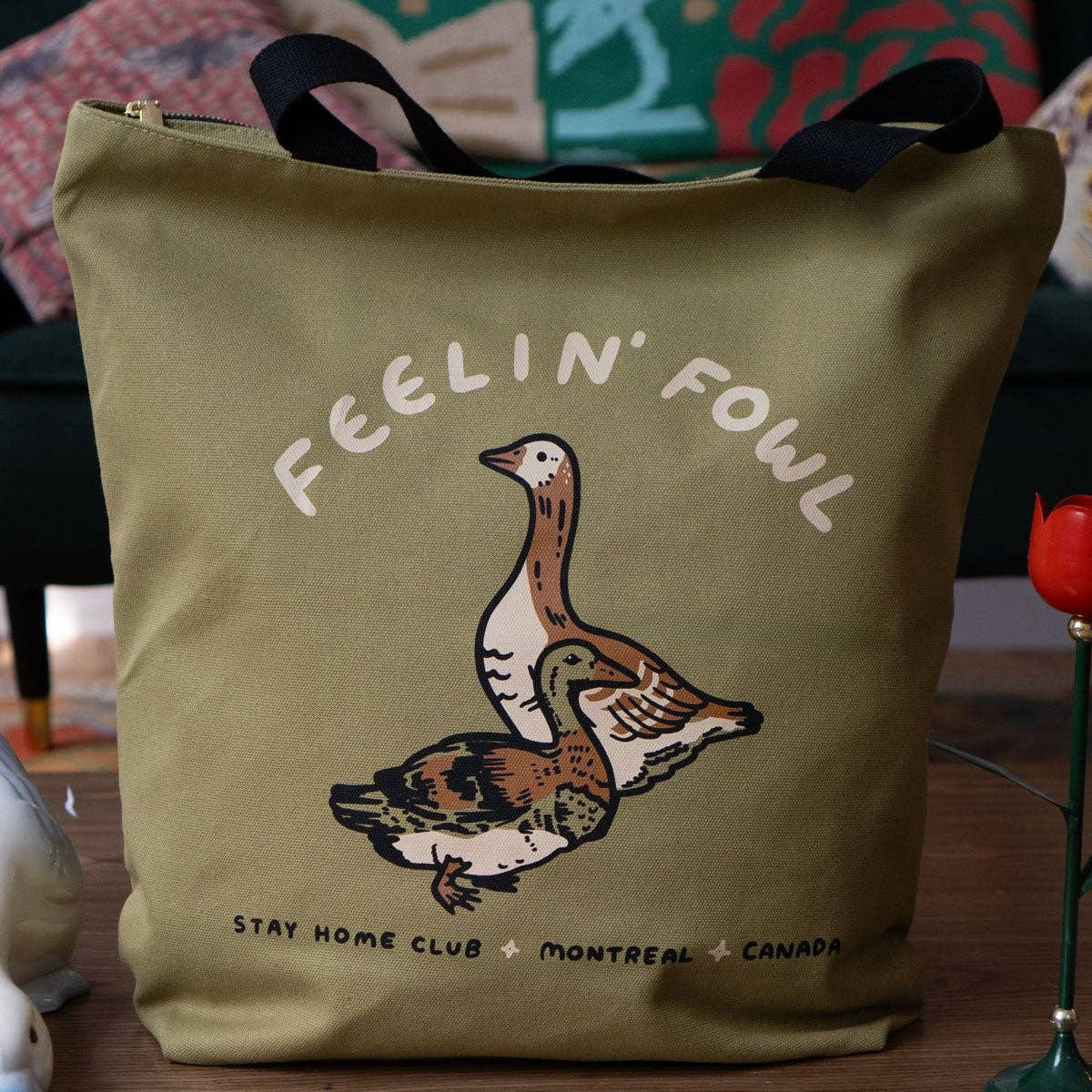 Green tote bag with duck illustration and text on a wooden surface