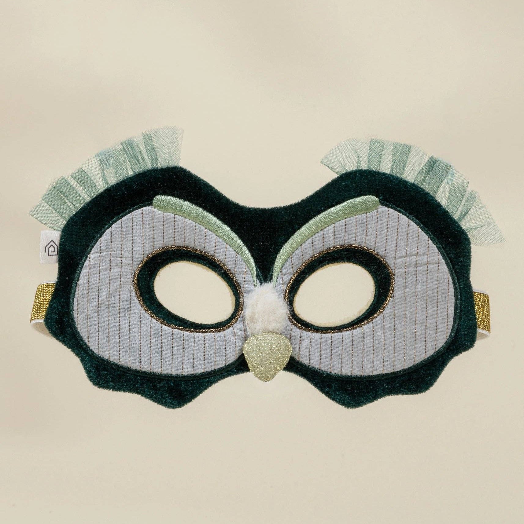 Owl-themed eye mask with green and white design on a beige background