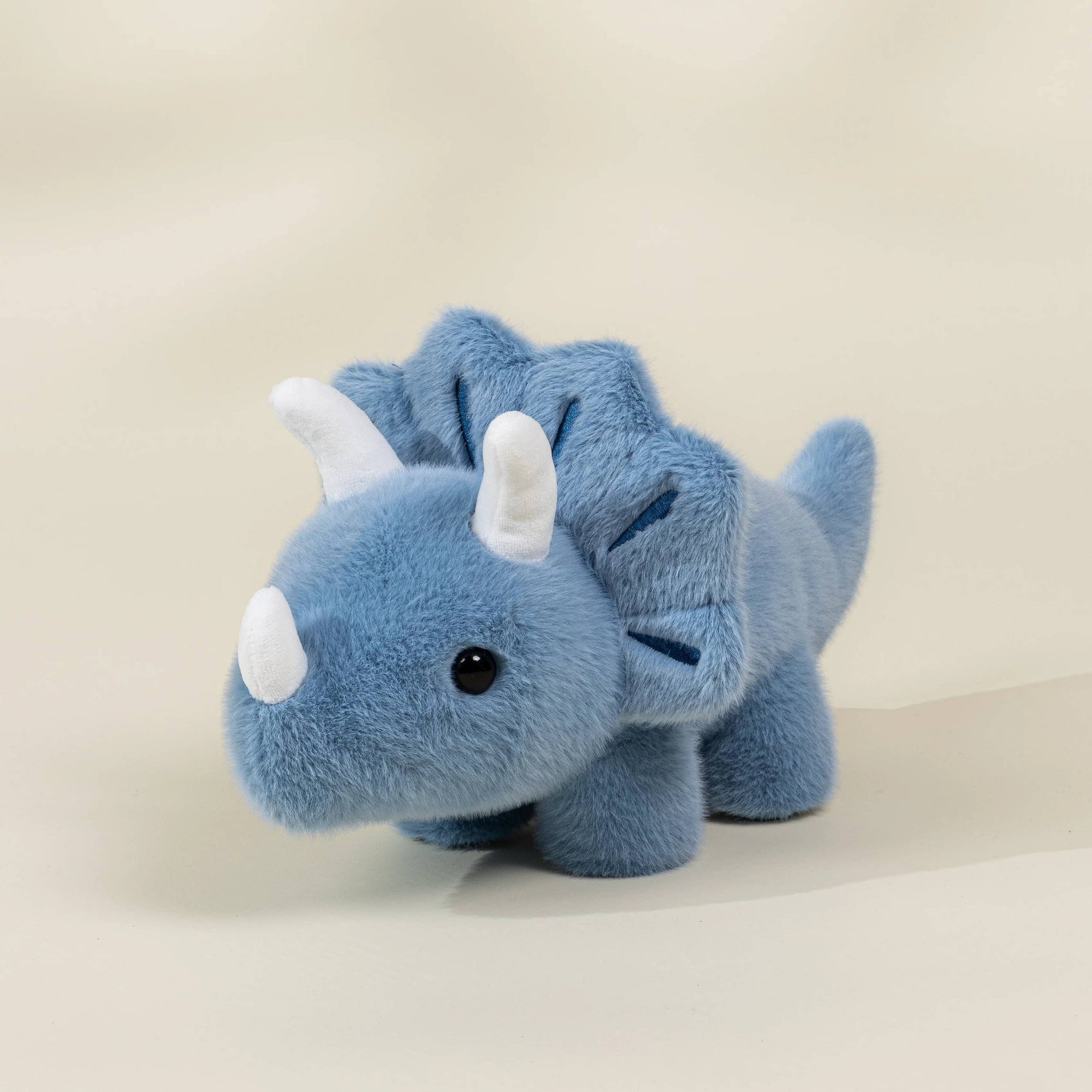 Blue plush dinosaur toy on a beige background