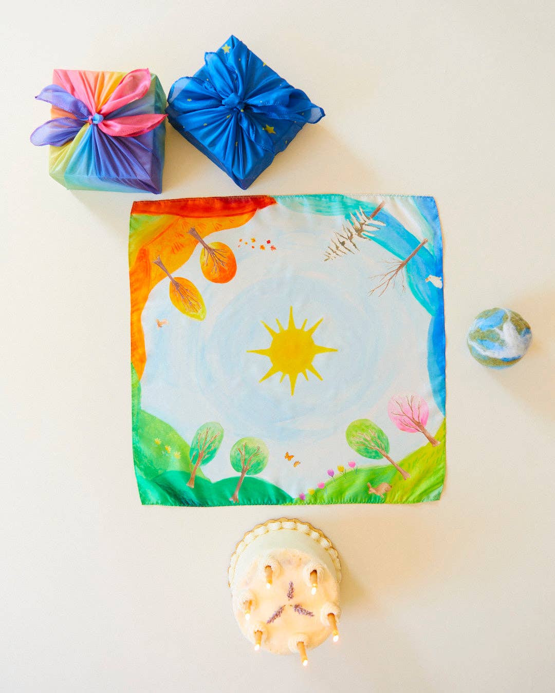 Gift bag with nature-themed design, colorful ribbons, and small decorative items on a light background