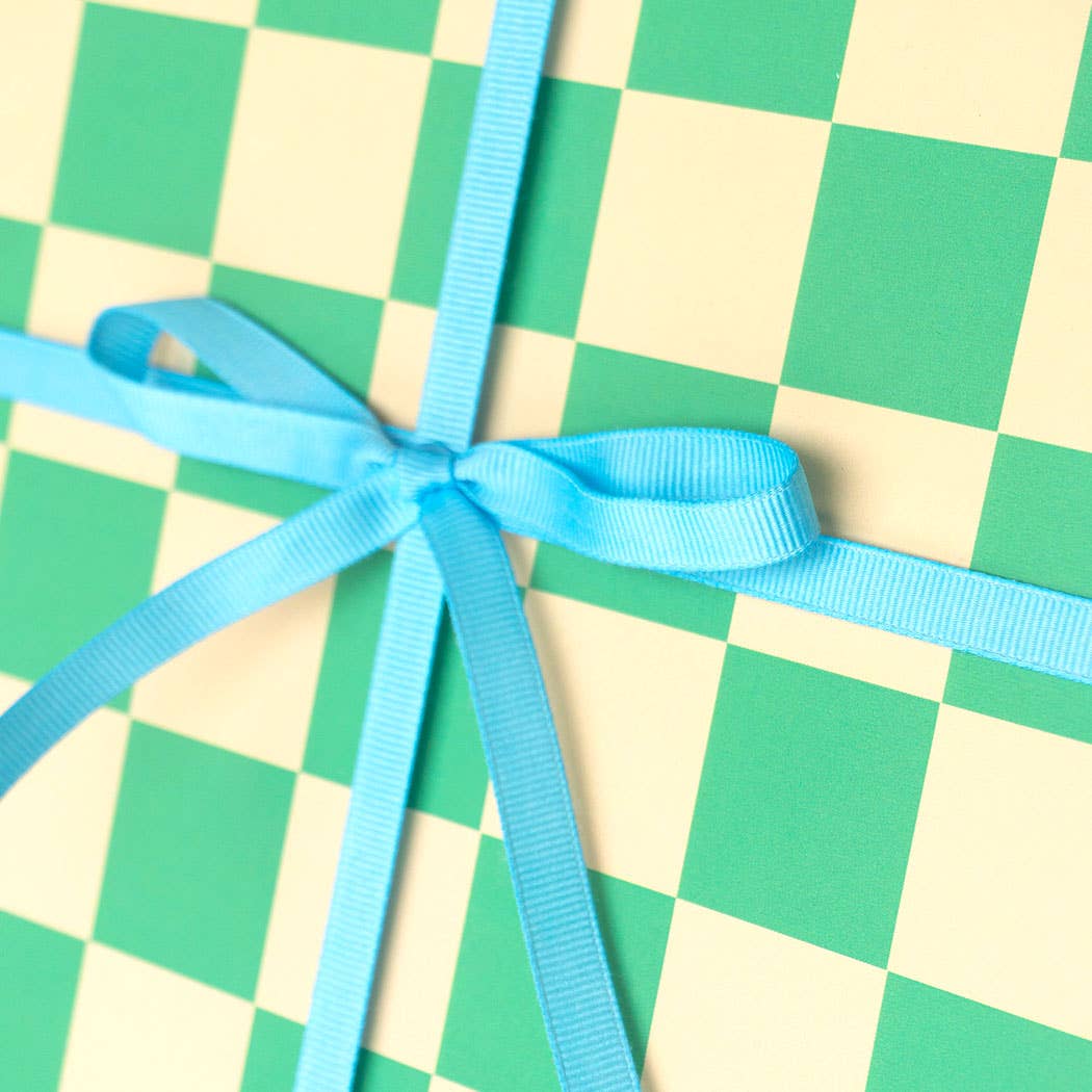 Blue ribbon tied in a bow on a green and beige checkered background