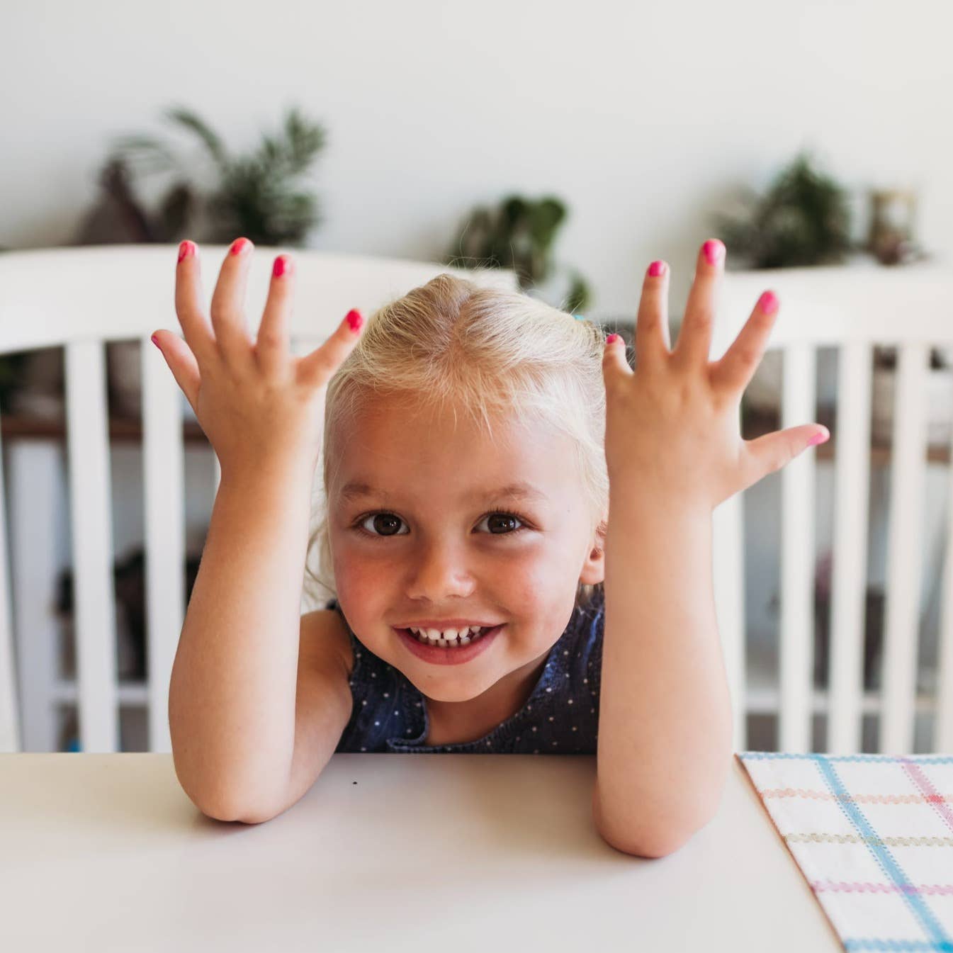 Child with hands raised on a table, smiling
