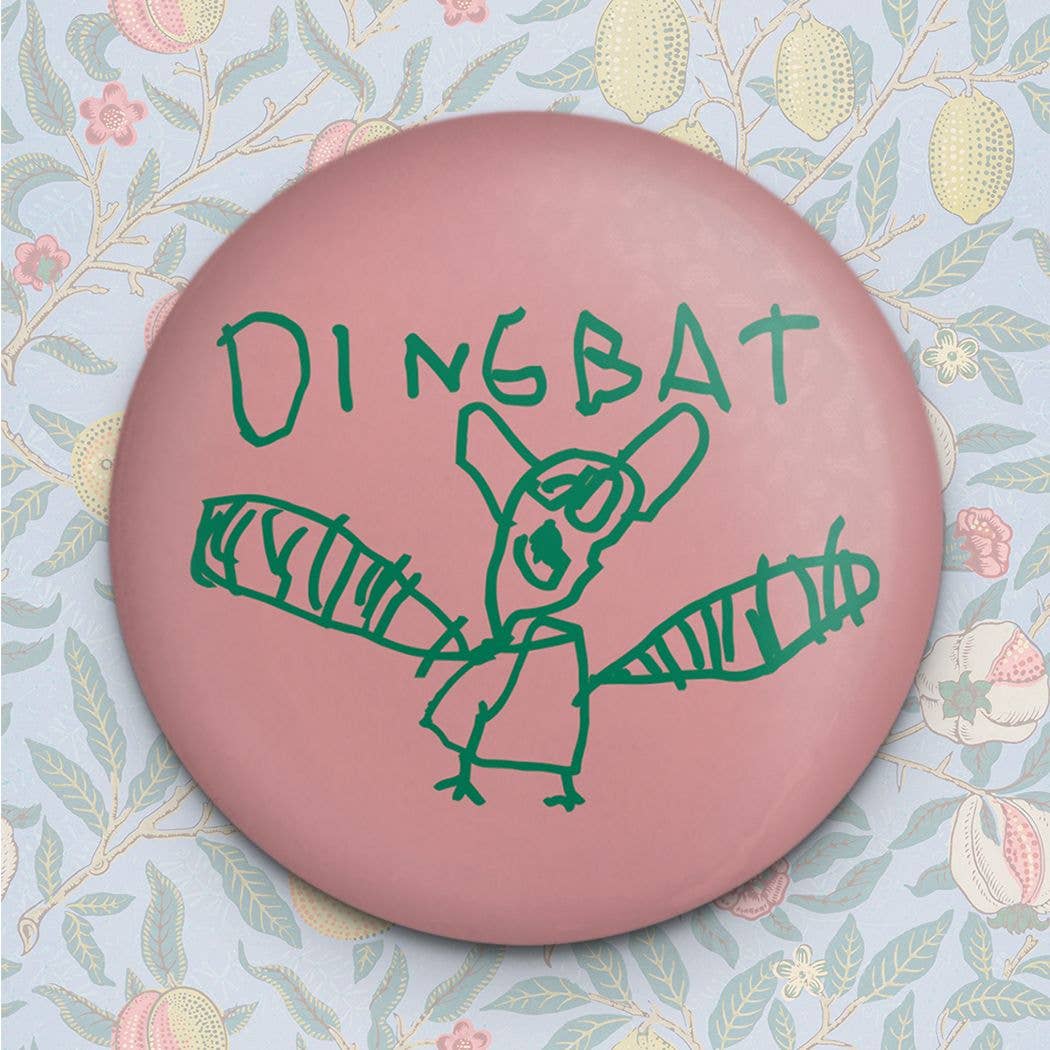 Pink button with green 'DINGBAT' logo on a floral background