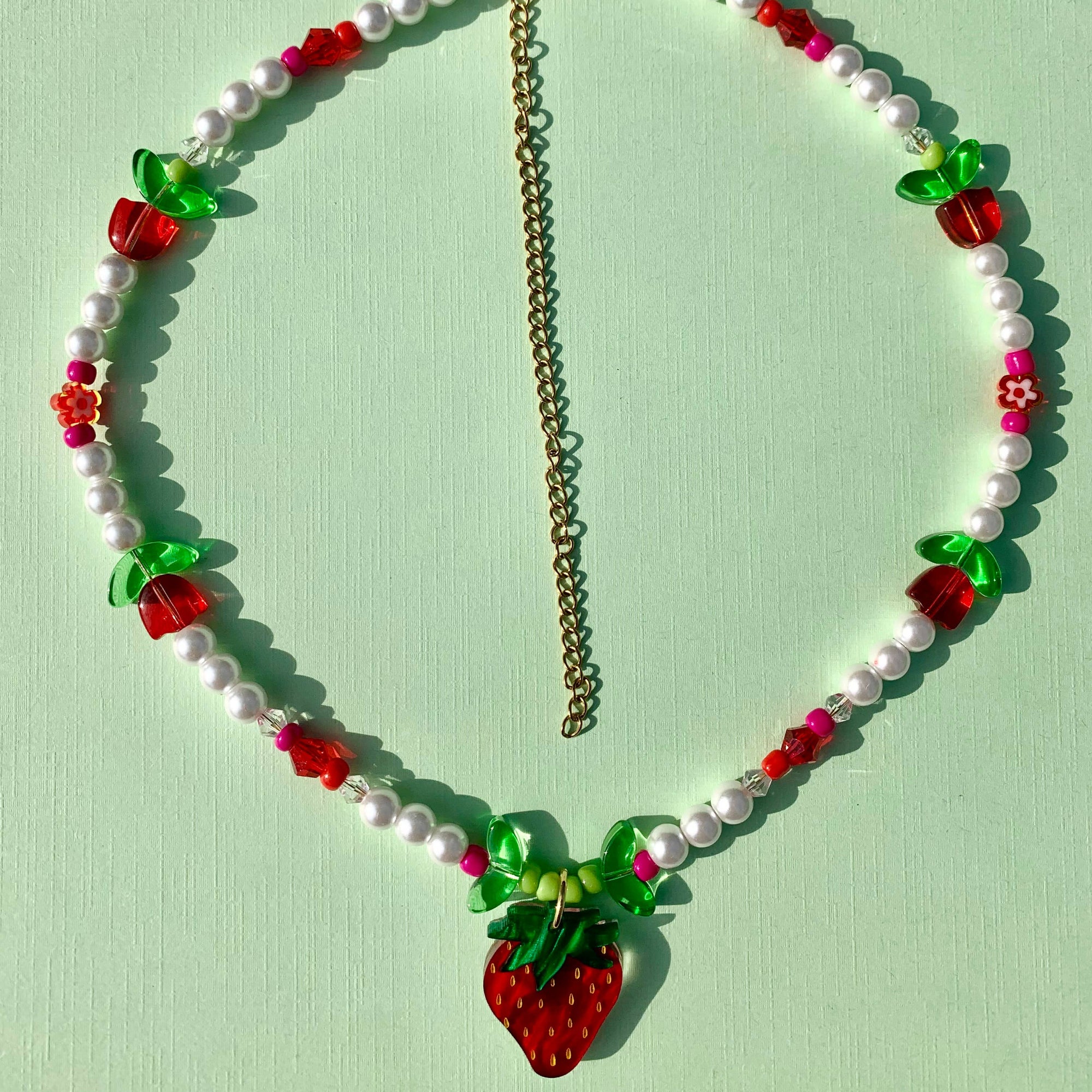 Necklace with strawberry-shaped beads on a light green background
