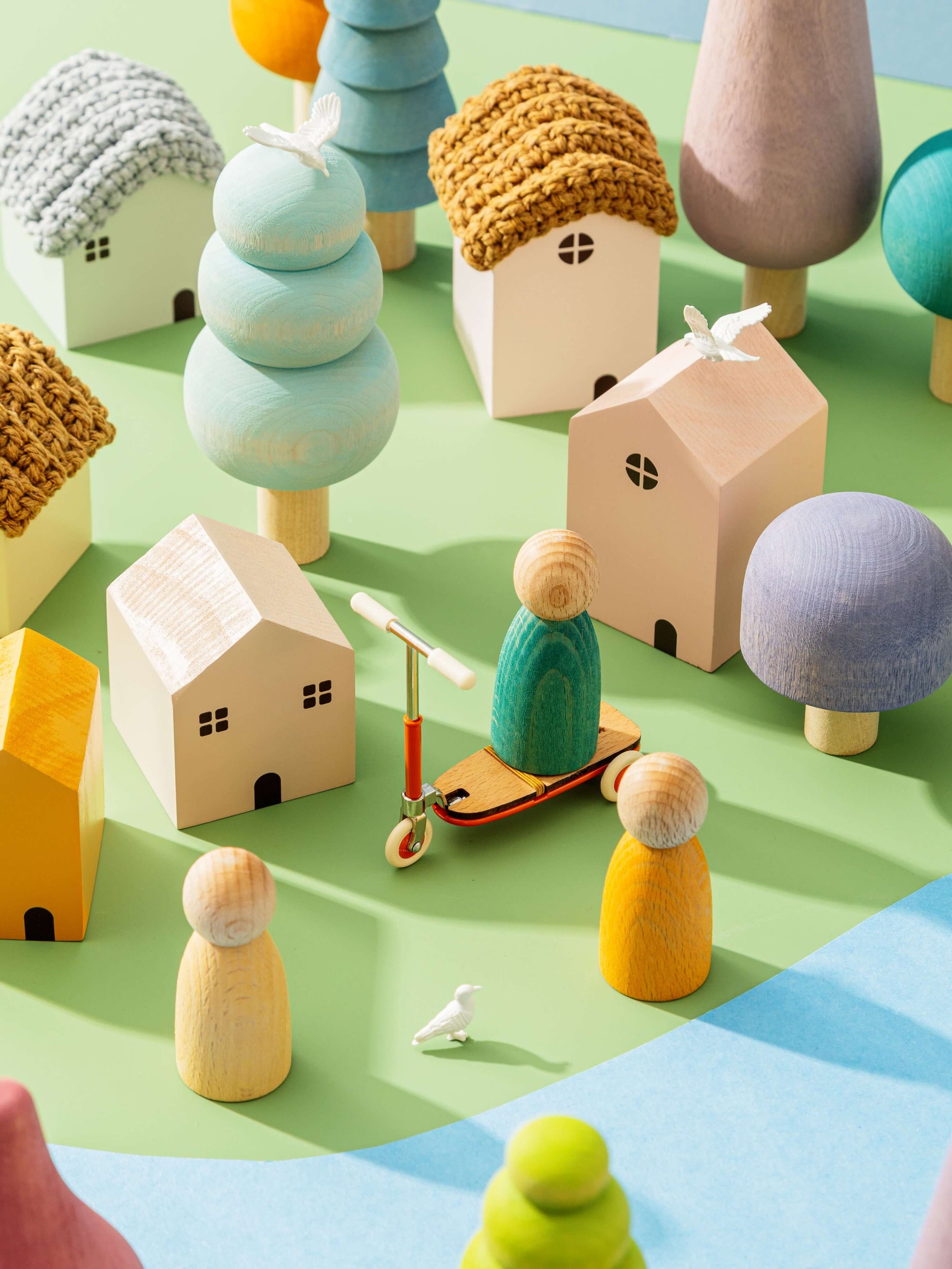 Colorful wooden toy houses and figures on a green surface