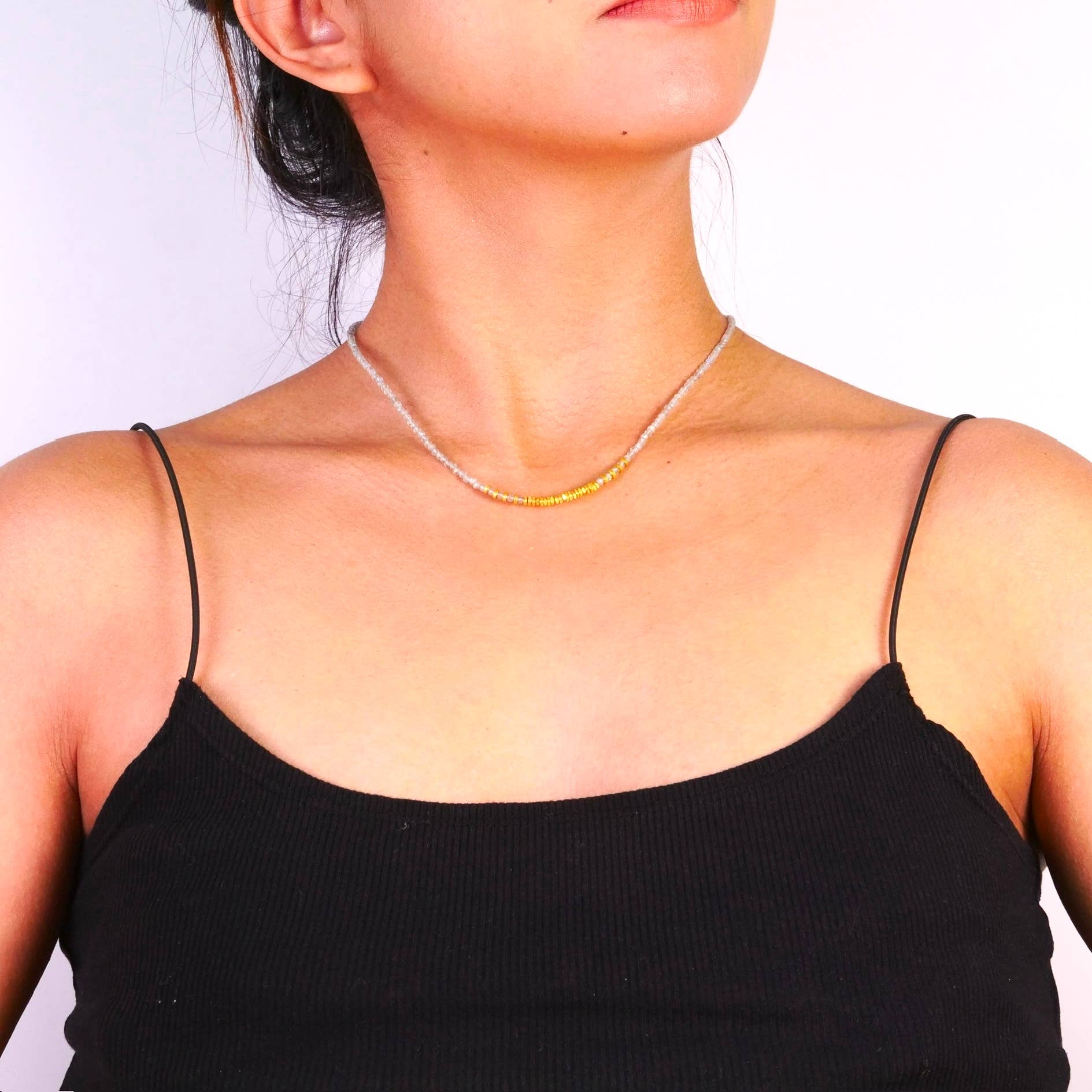 Woman wearing a delicate necklace against a plain background