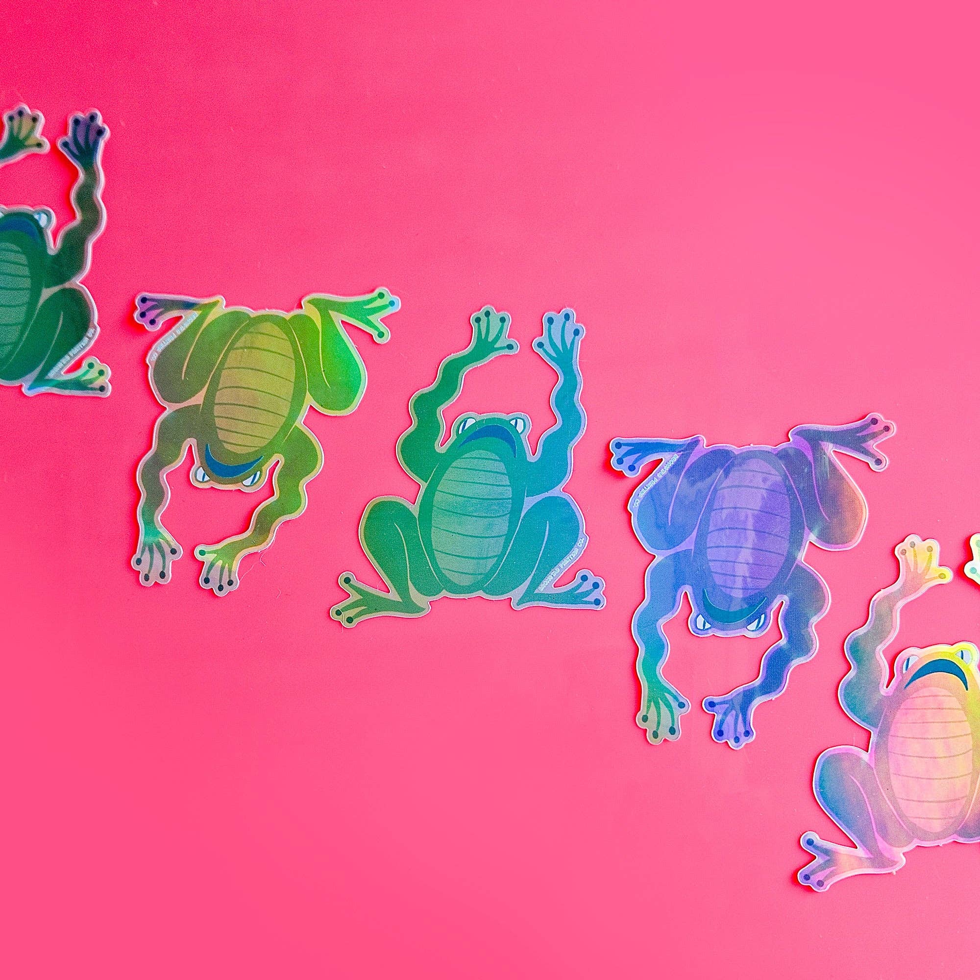 Colorful frog sticers on a pink background