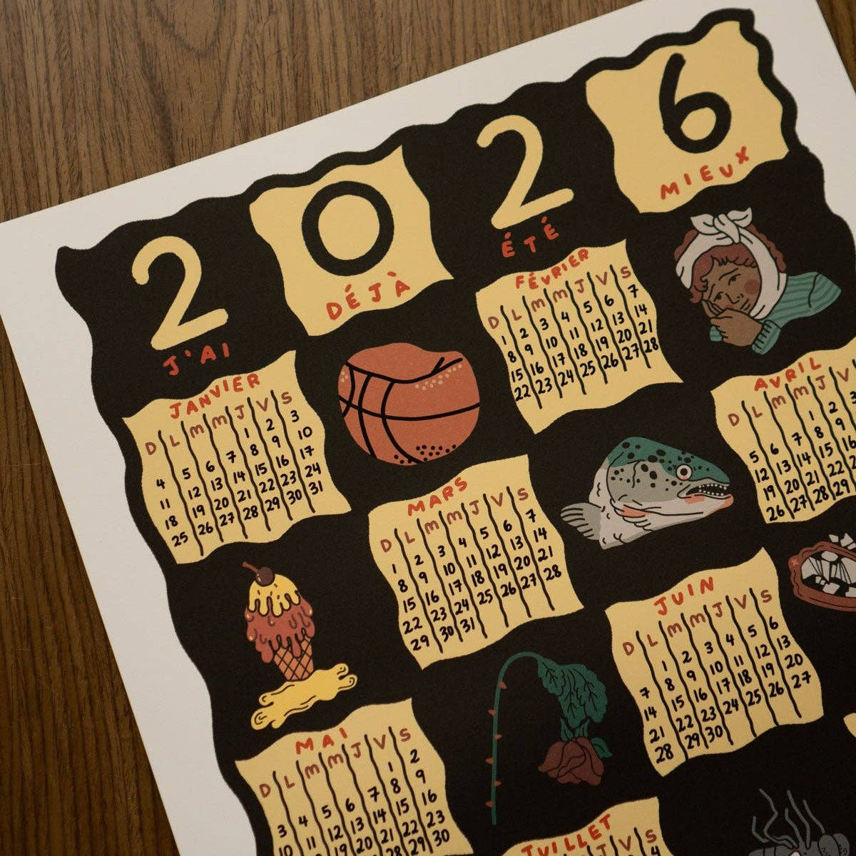 Calendar for the year 2026 with various illustrations on a wooden surface