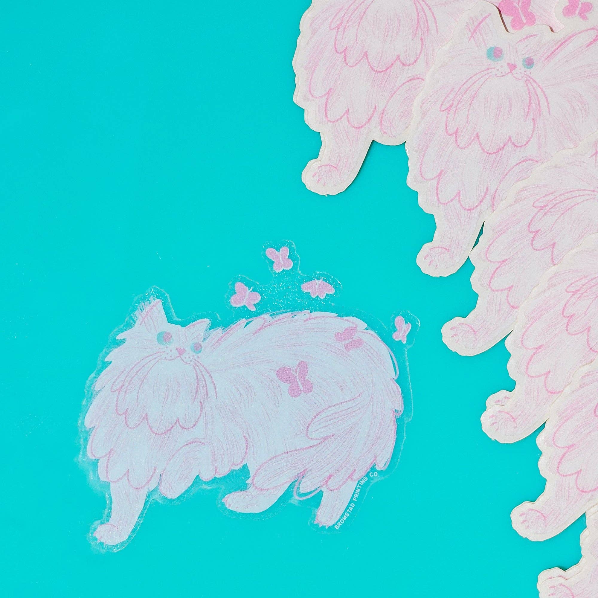 Pink cartoon-style cat and butterfly sticker on a turquoise background