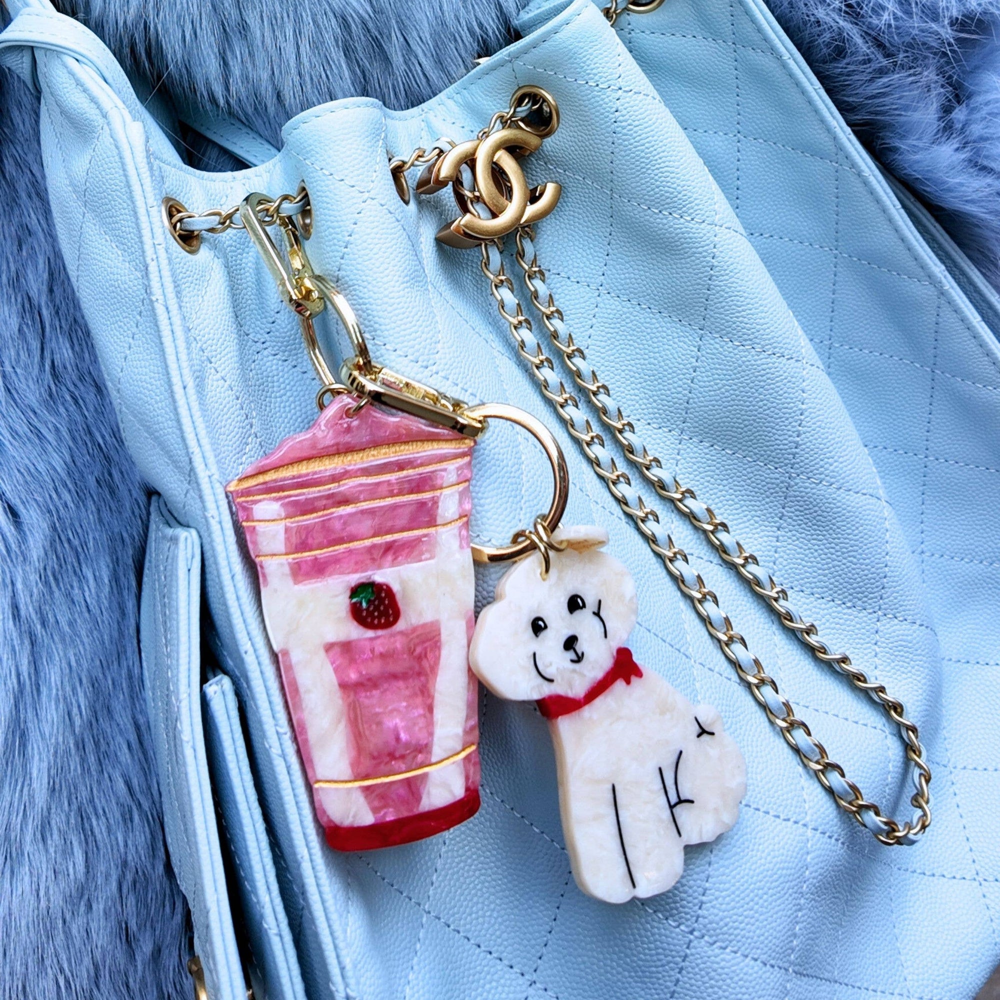 Keychain with a coffee cup and dog charm attached to a blue handbag.