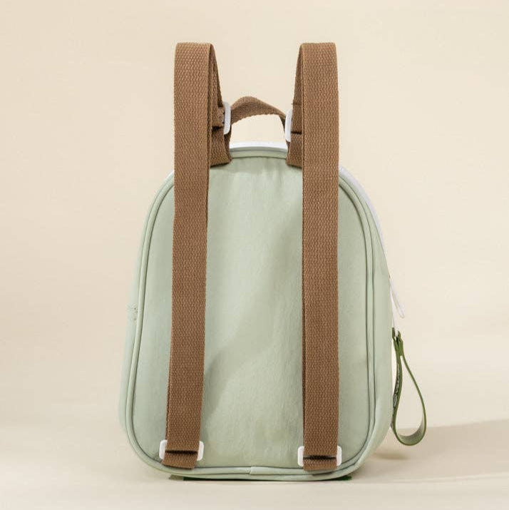 Small green backpack with brown straps on a beige background