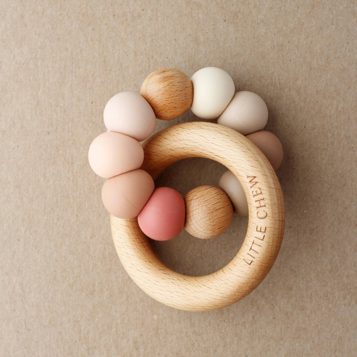 Wooden teething ring with colorful beads on a beige background