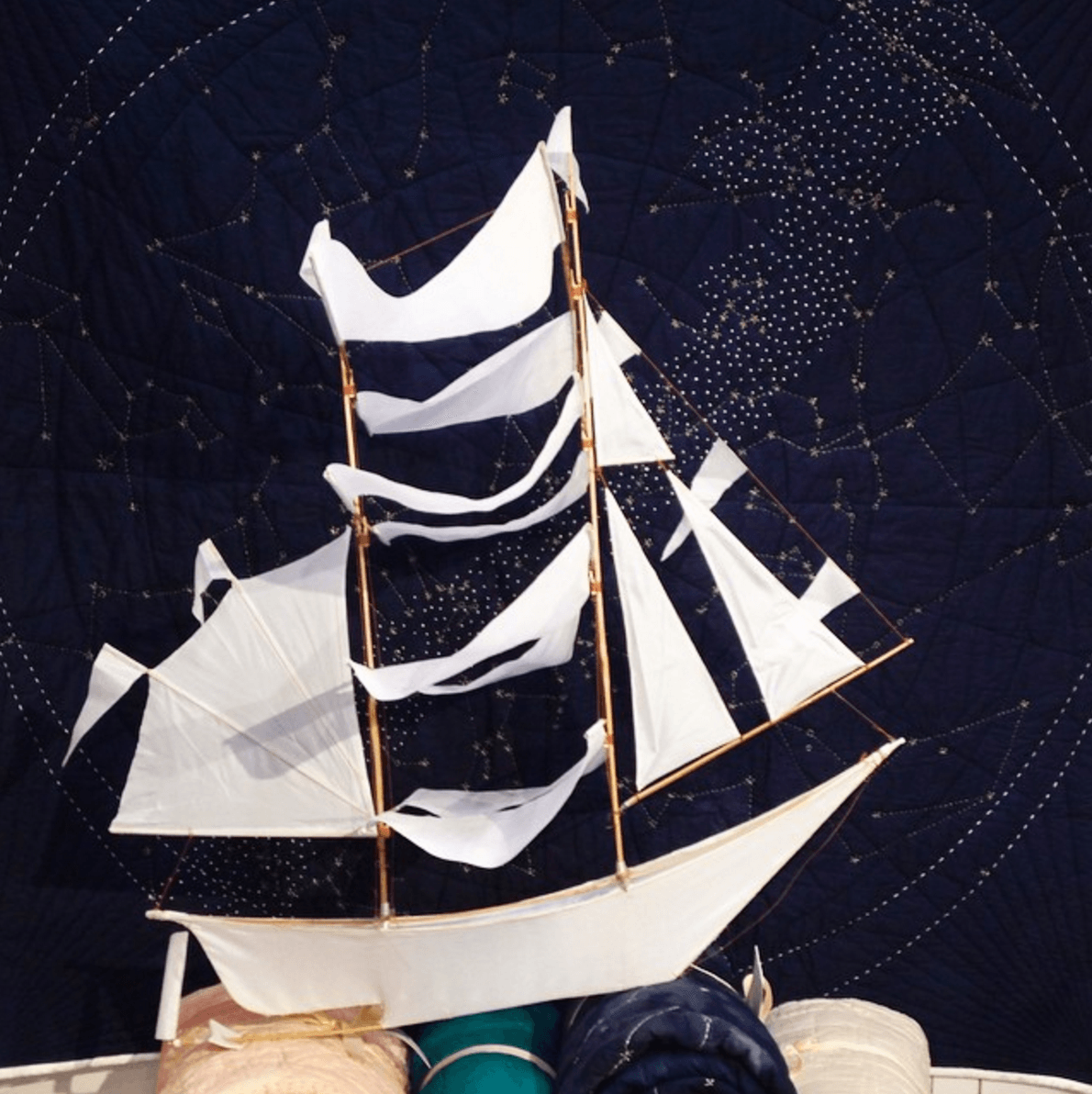 Model ship with white sails against a starry night sky