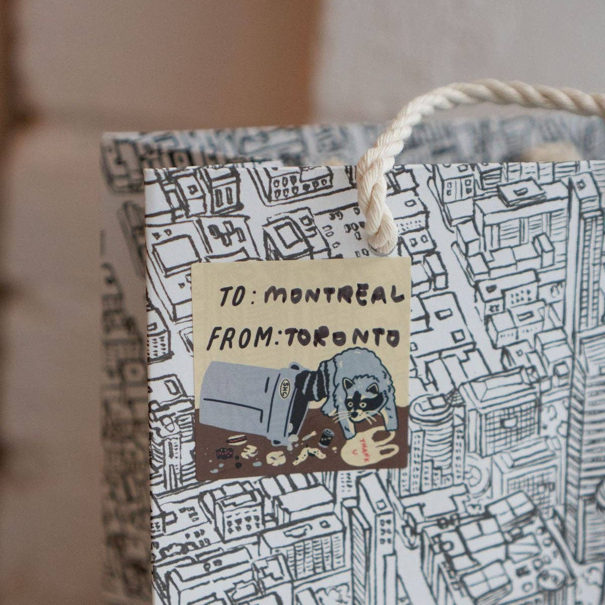 Gift bag with map design and 'To: Montreal From: Toronto' text on a blurred background