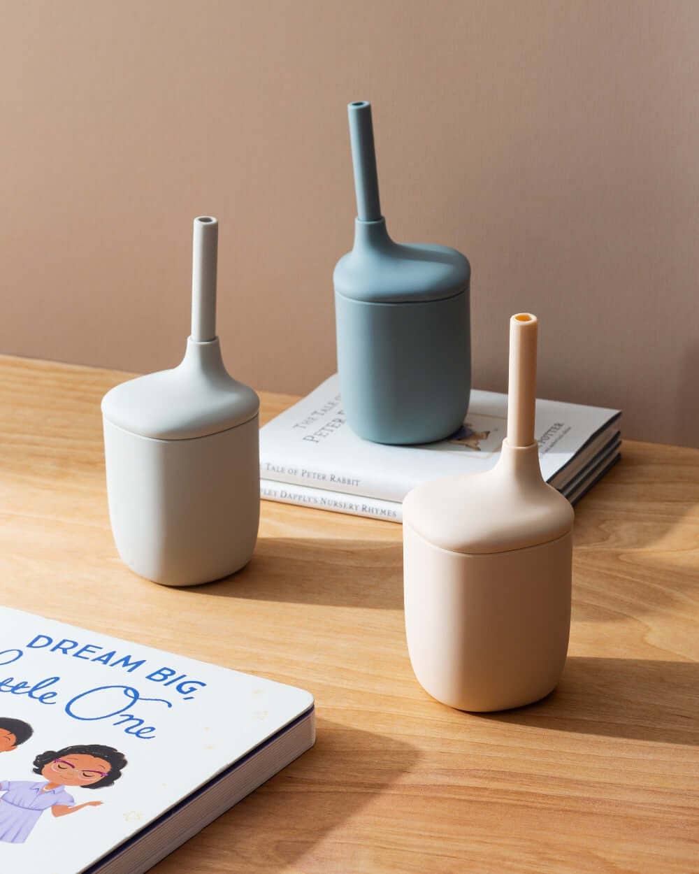 Three silicone containers on a wooden surface with a book underneath.