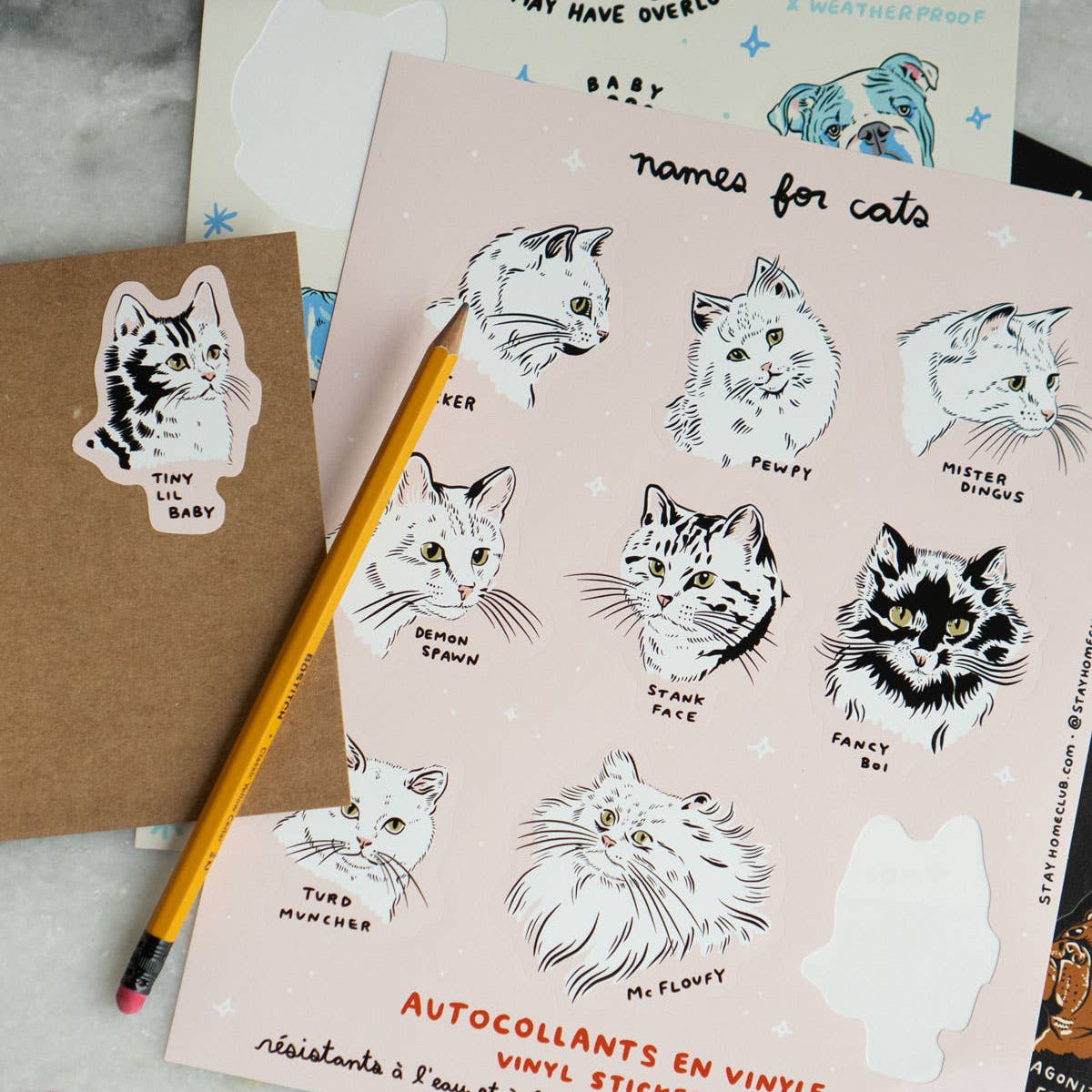 Cat-themed sticker sheets with a pencil on a textured surface