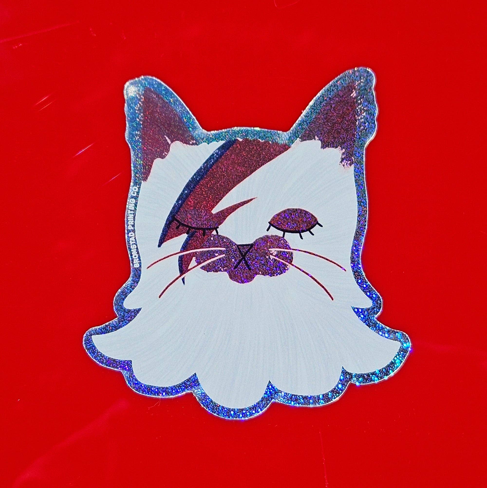 Cat-shaped sticker with glittery edges on a red background