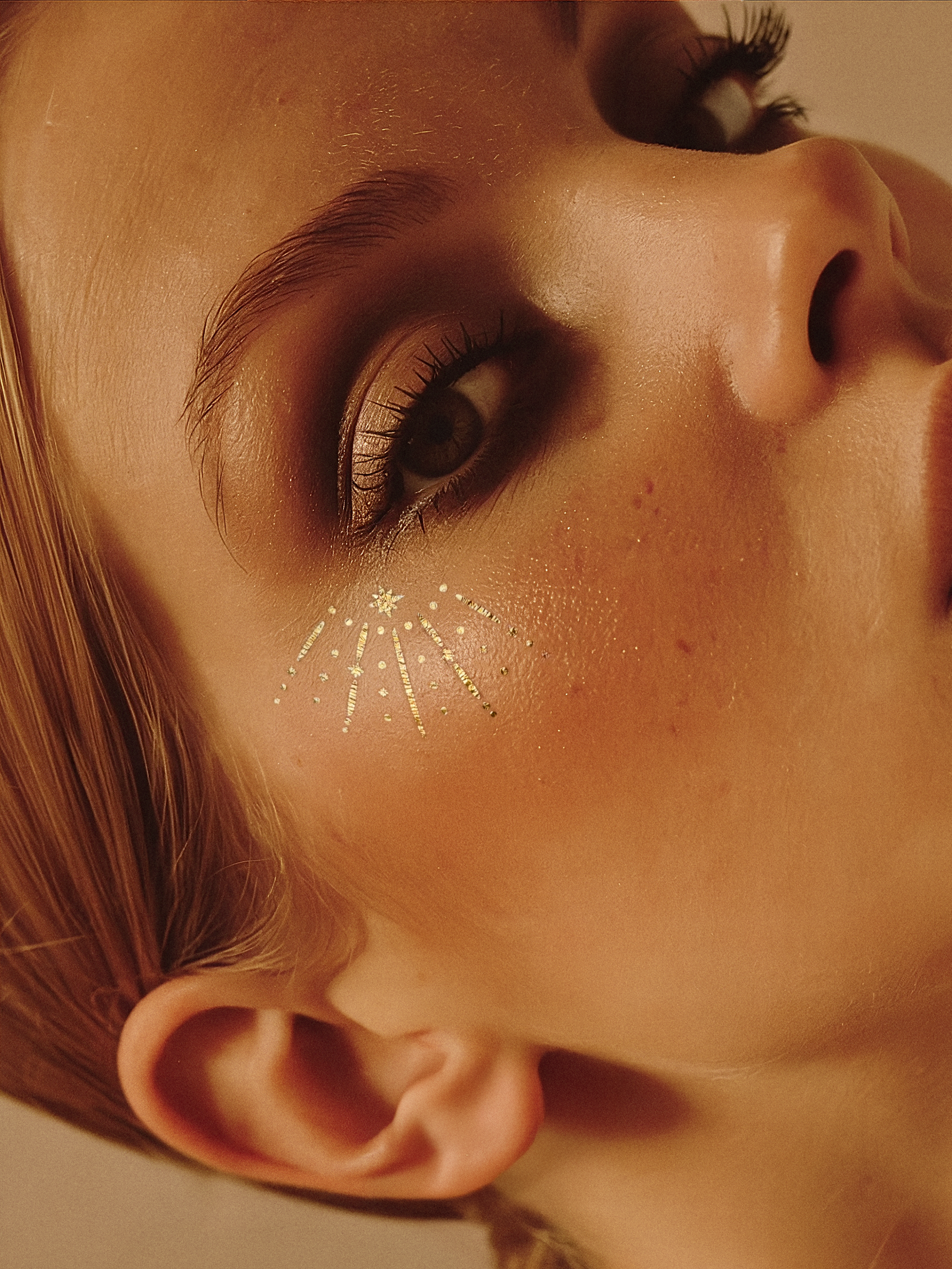 Close-up of a woman's face with a star-shaped temporary tattoo on her cheek.